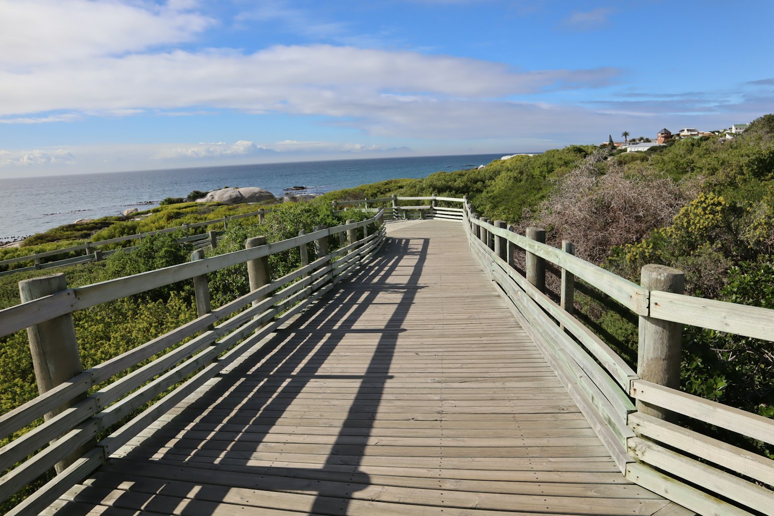Pasarela de madera que conduce al mar con cielo azul