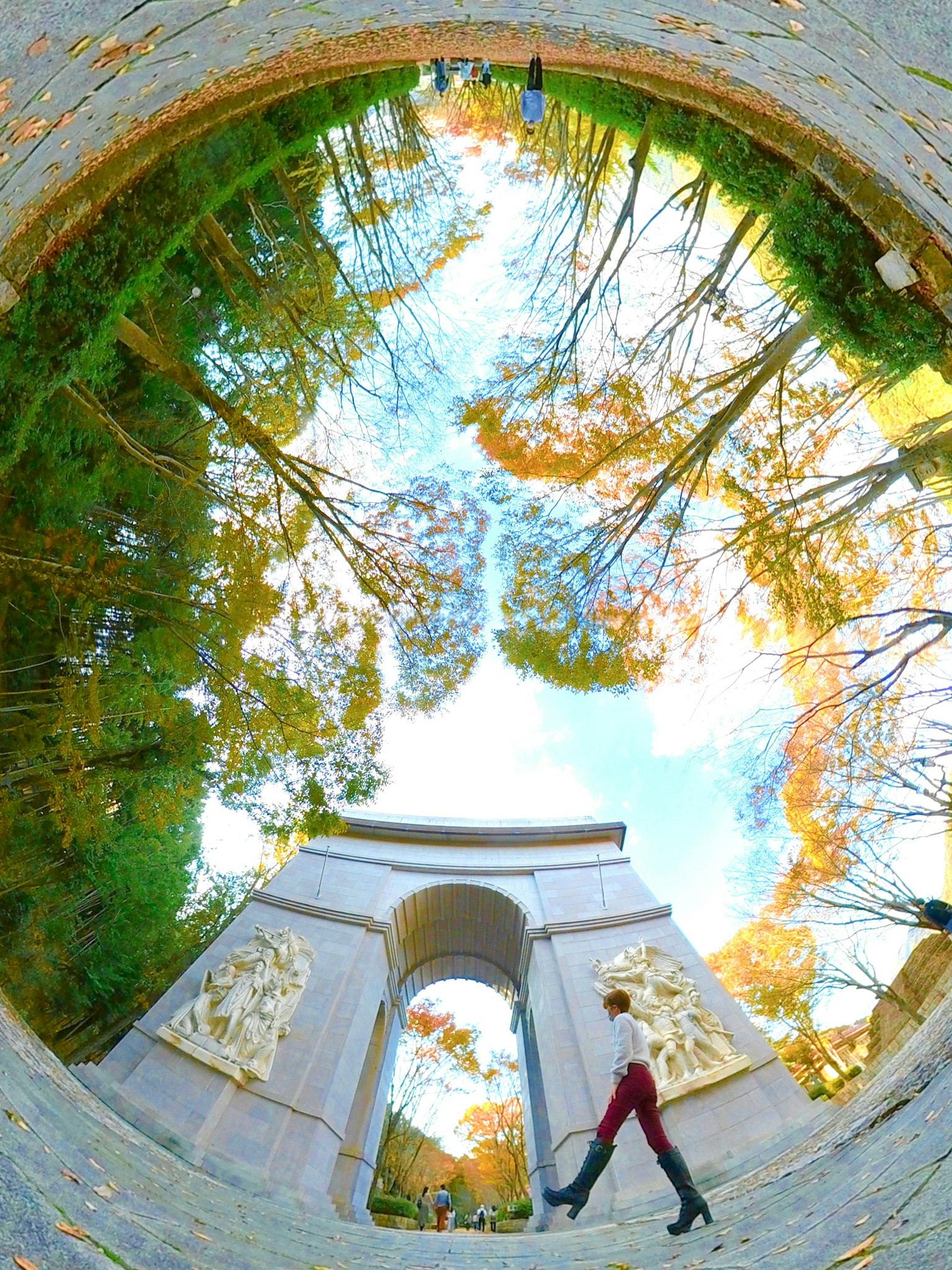 Une femme marchant devant une arche avec des reflets d'arbres et de ciel