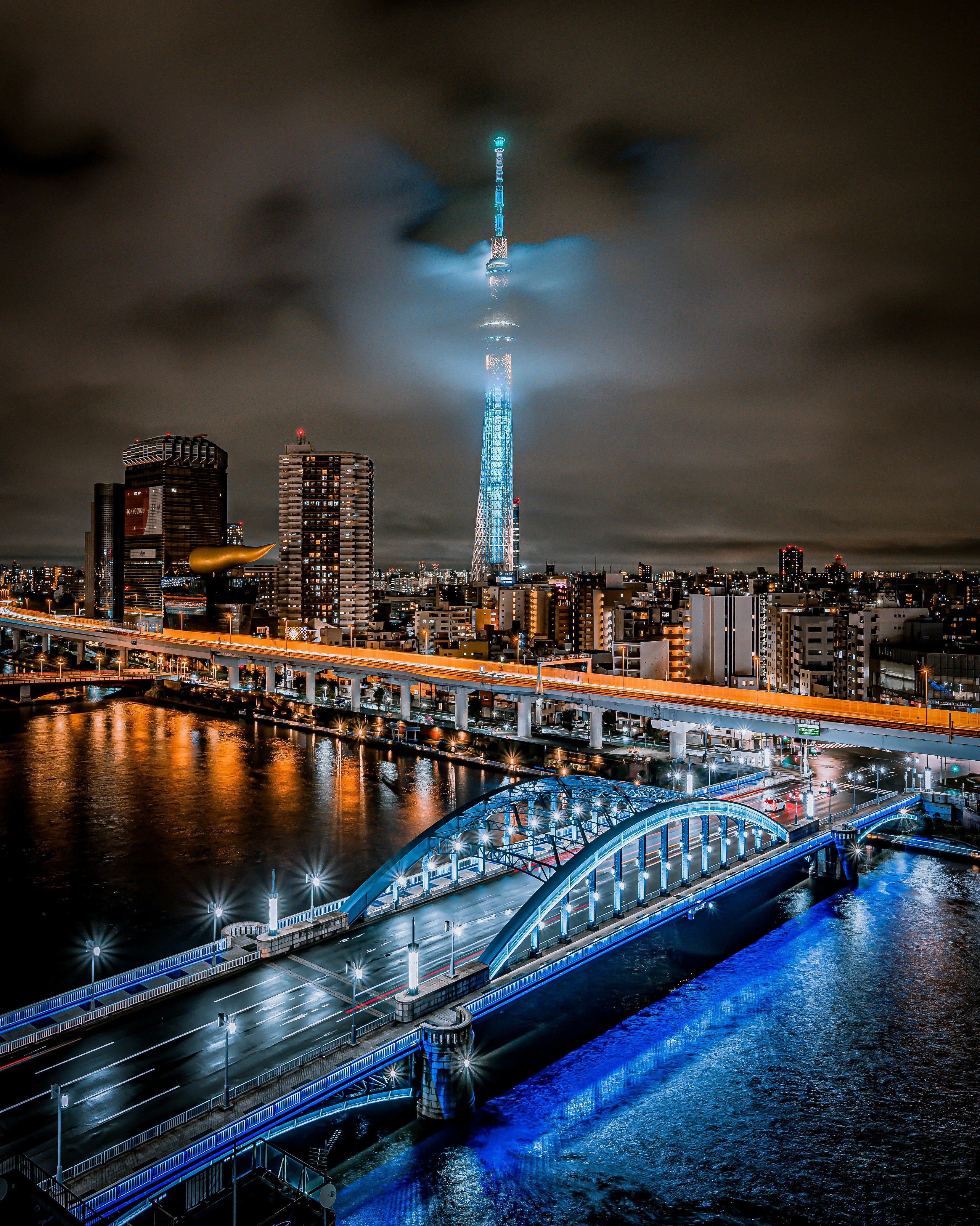 Tokyo Skytree under clouds with a riverside night view
