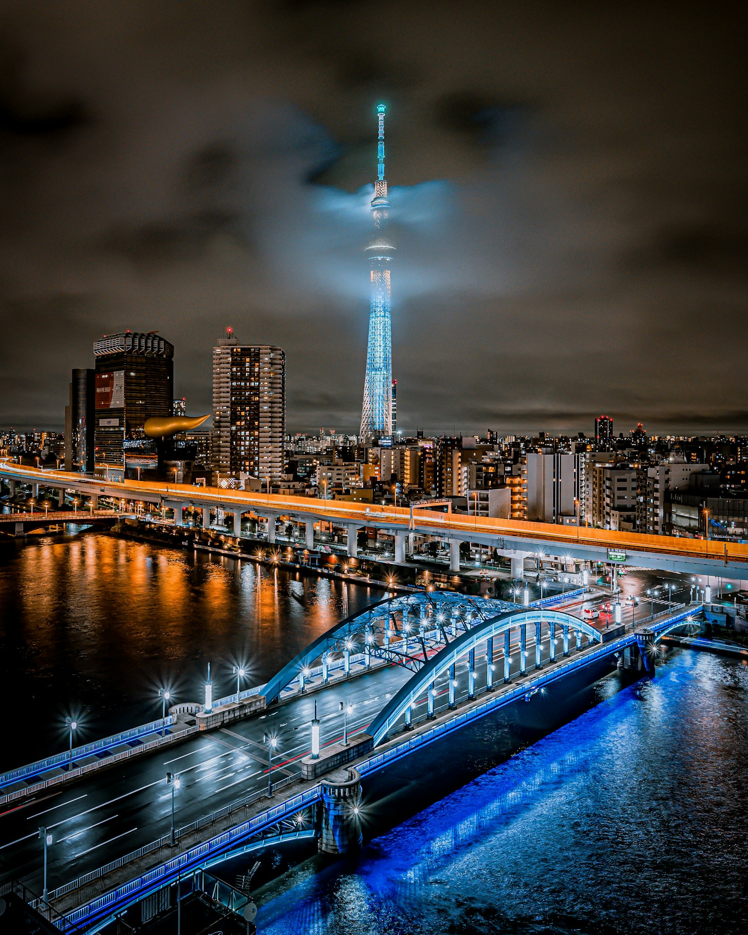 Nachtansicht des Tokyo Skytree und einer Brücke mit Stadtlichtern