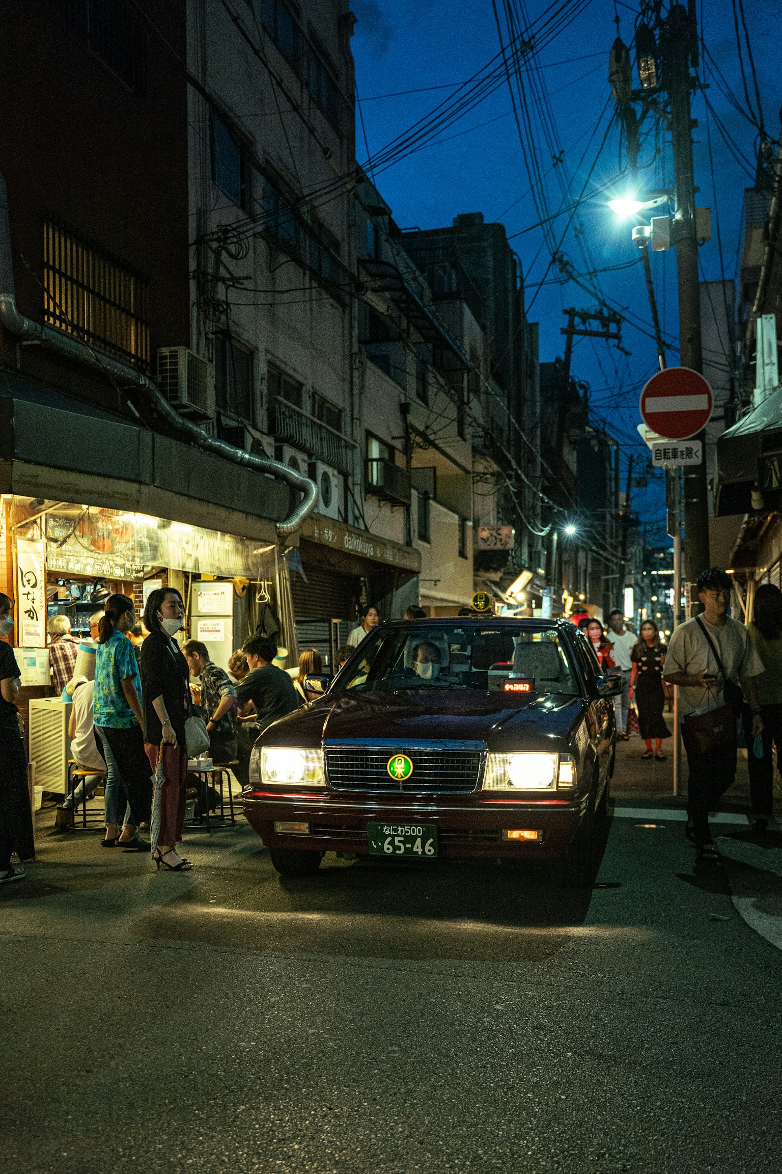 Un taxi in una strada affollata di notte con persone e negozi