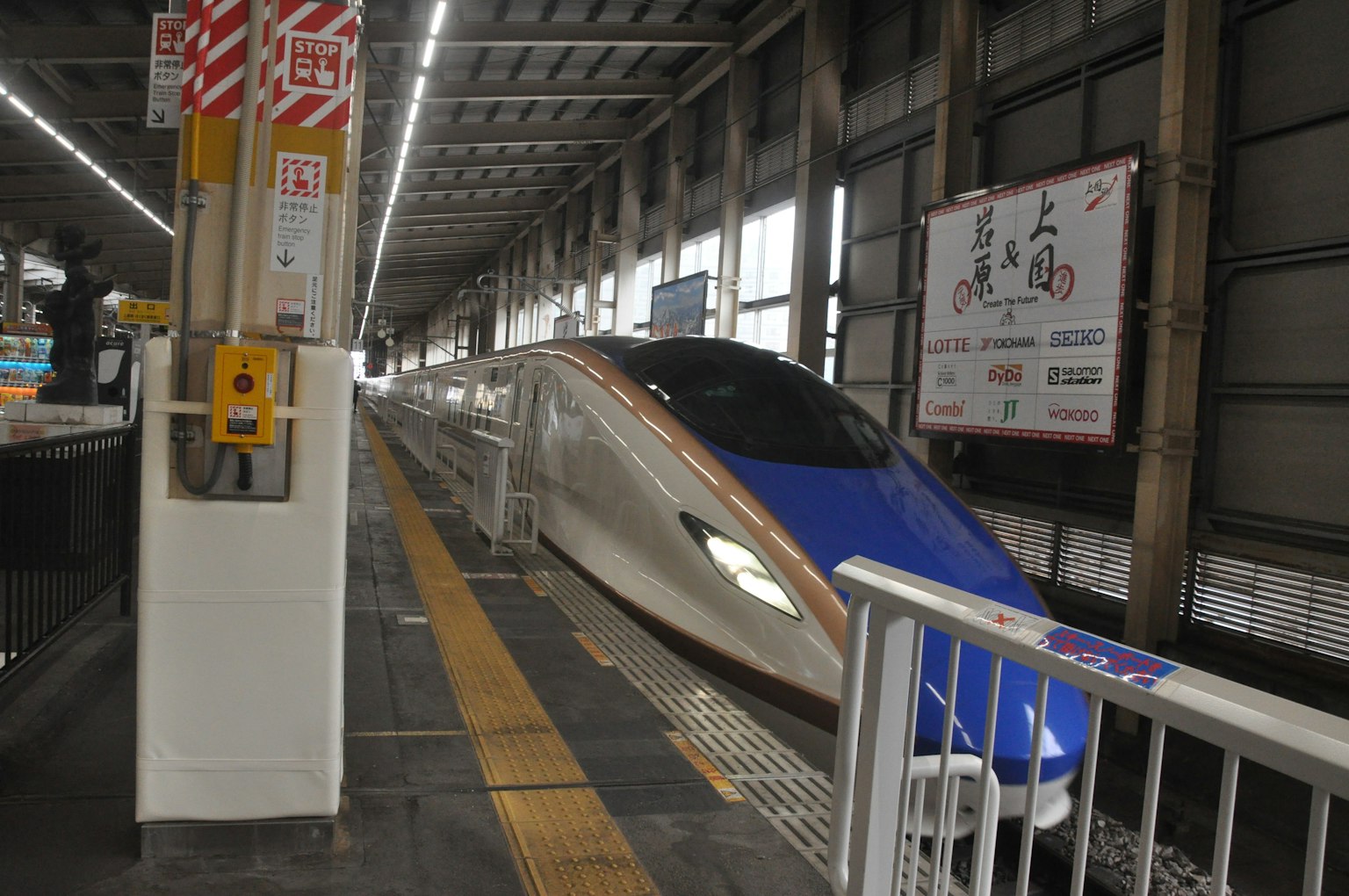Tàu Shinkansen tại ga với thân màu xanh và các điểm nhấn màu vàng