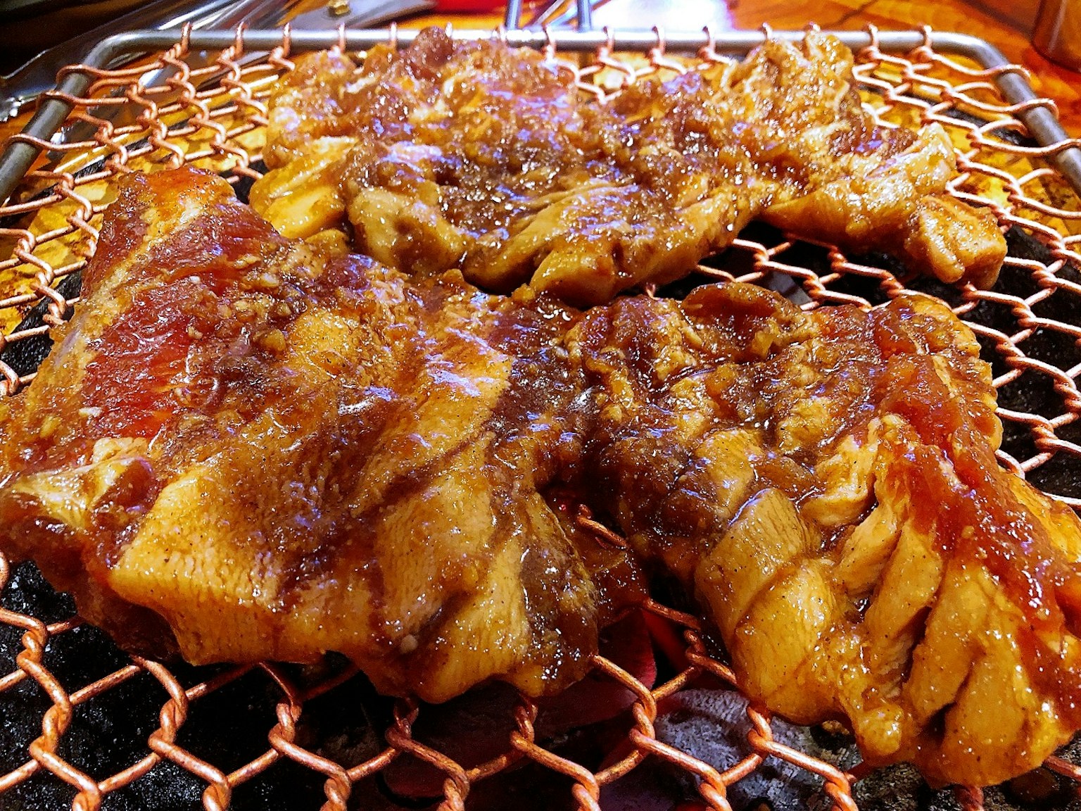 Foto di carne grigliata con una salsa scura che brilla sulla superficie