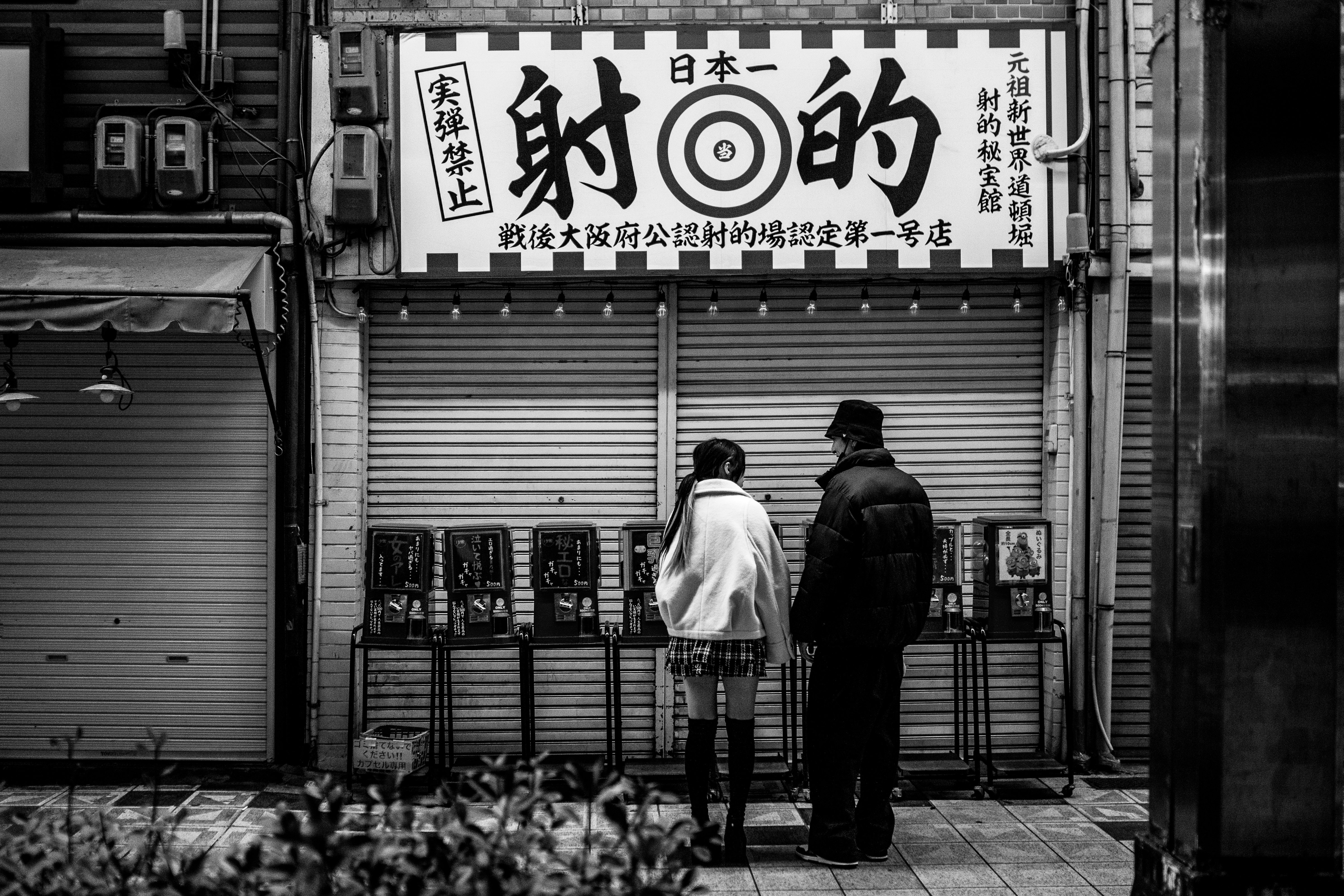 大坂・新世界の閉店シャッター前に立つ2人の後ろ姿