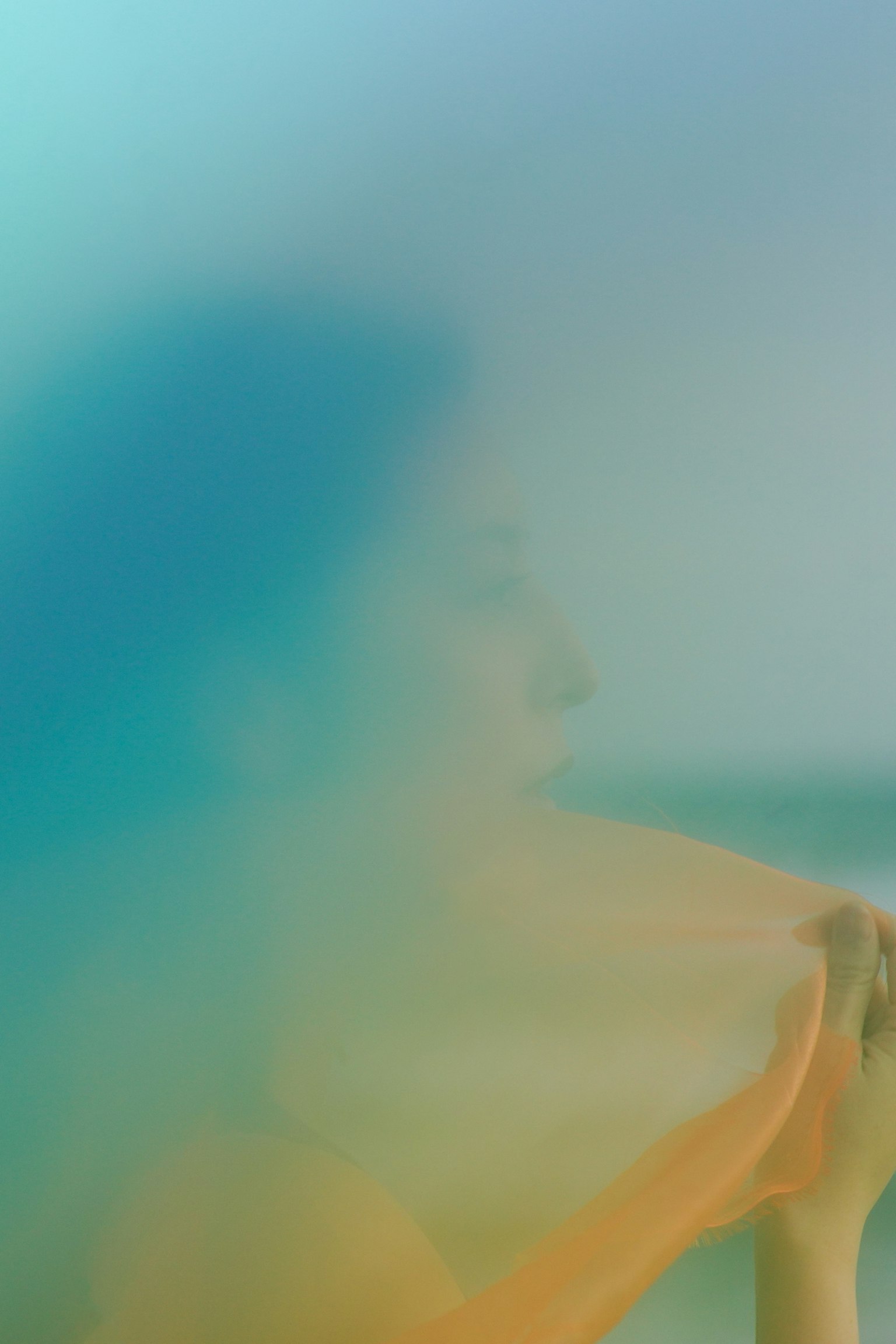 Una donna parzialmente visibile con uno sfondo sfocato e colori tenui