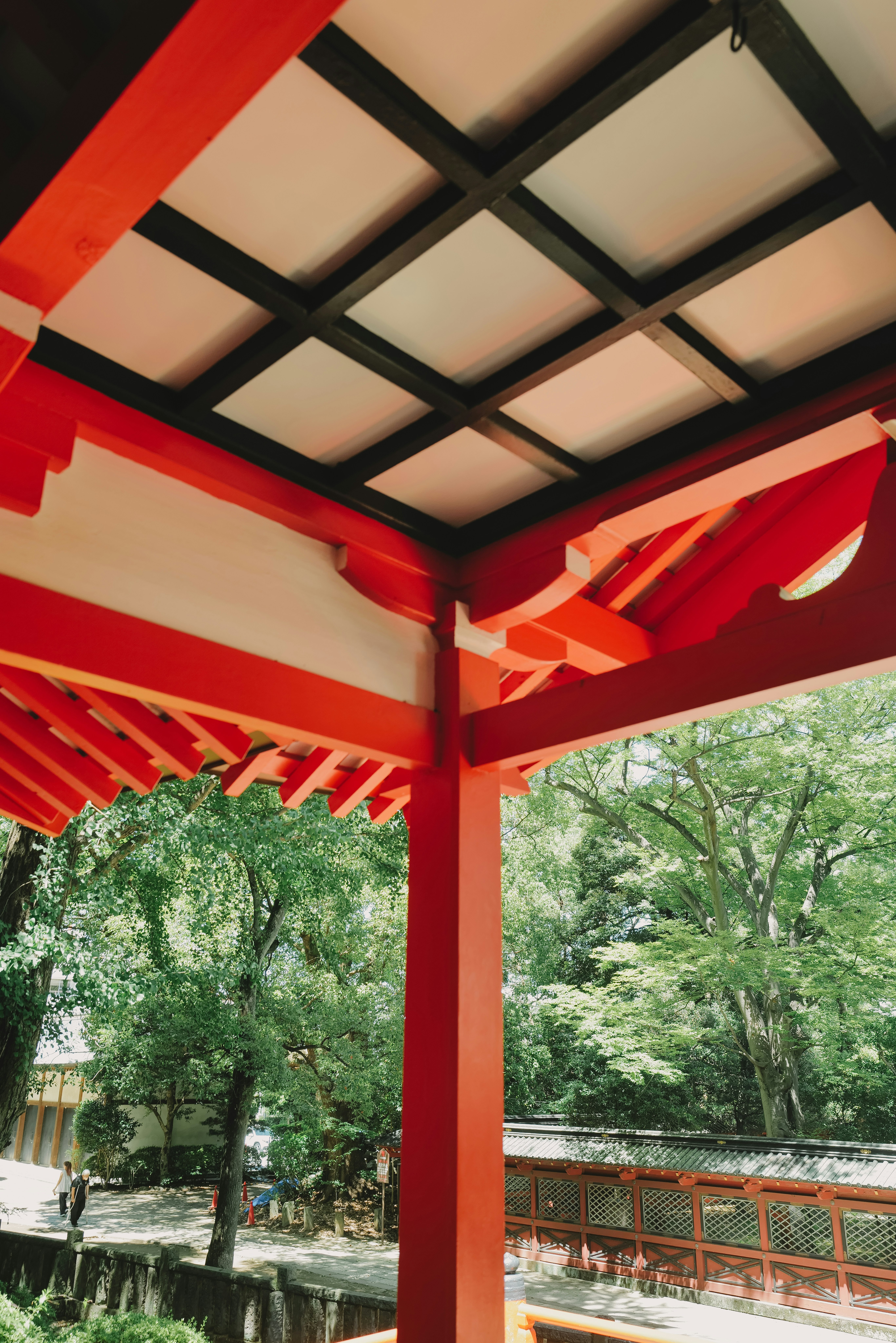 View of a vermilion-painted corridor with a lattice roof over a garden