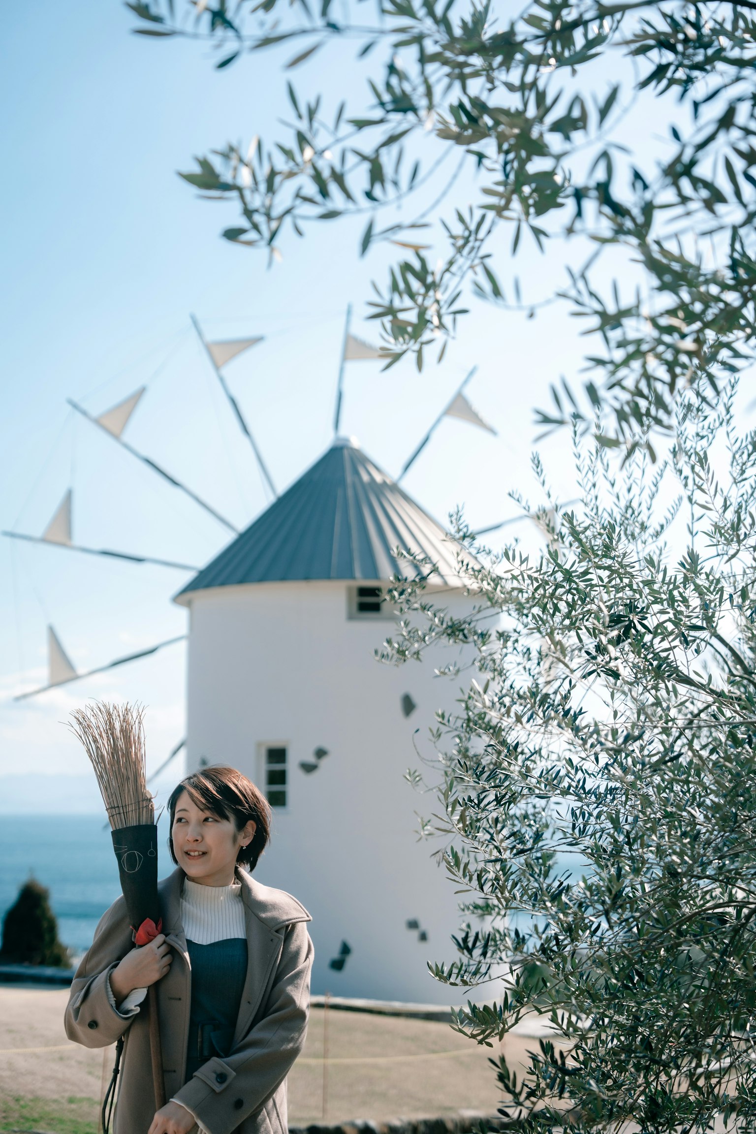 Femme se tenant devant un moulin à vent avec un olivier