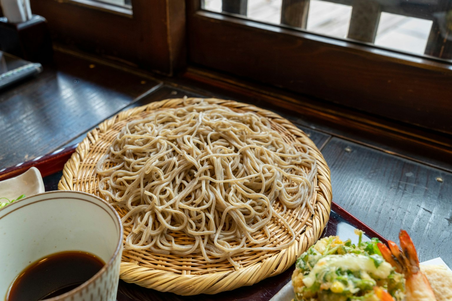Fideos soba japoneses servidos en una canasta tejida con salsa para mojar