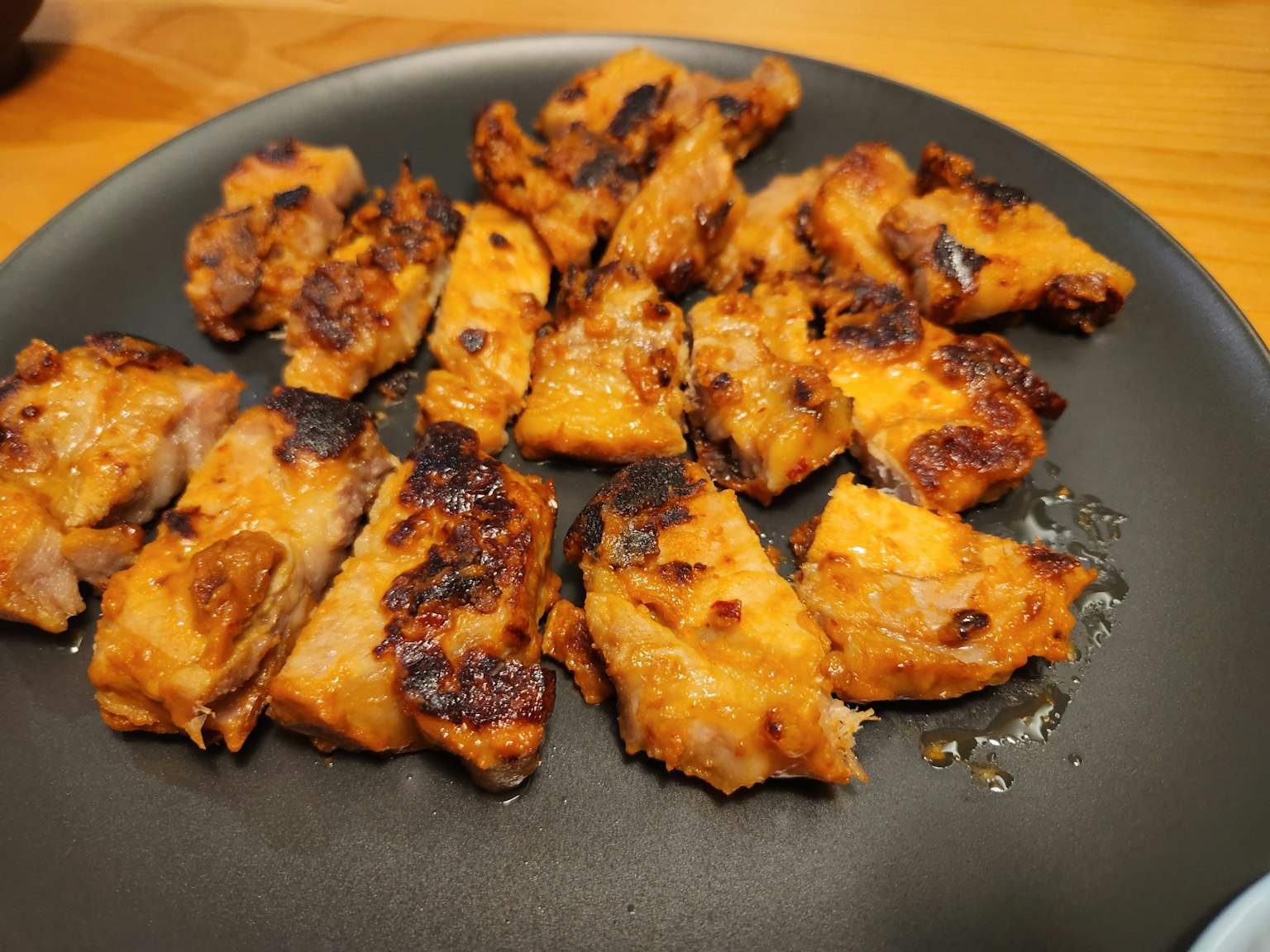 Piatto di pezzi di pollo grigliato disposti su un piatto nero