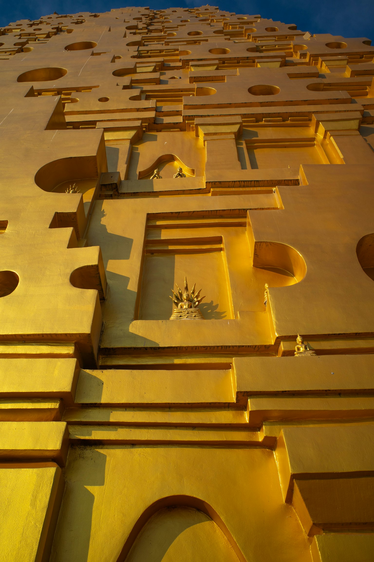 Einzigartige Formen und Dekorationen an einer goldenen Gebäudewand mit Löchern