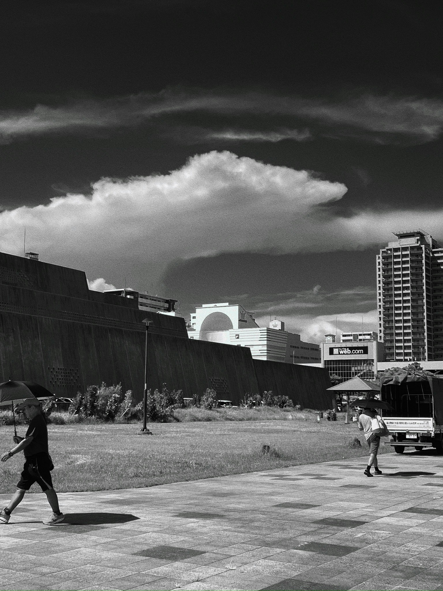 Black and white urban scene with pedestrians buildings and clouds