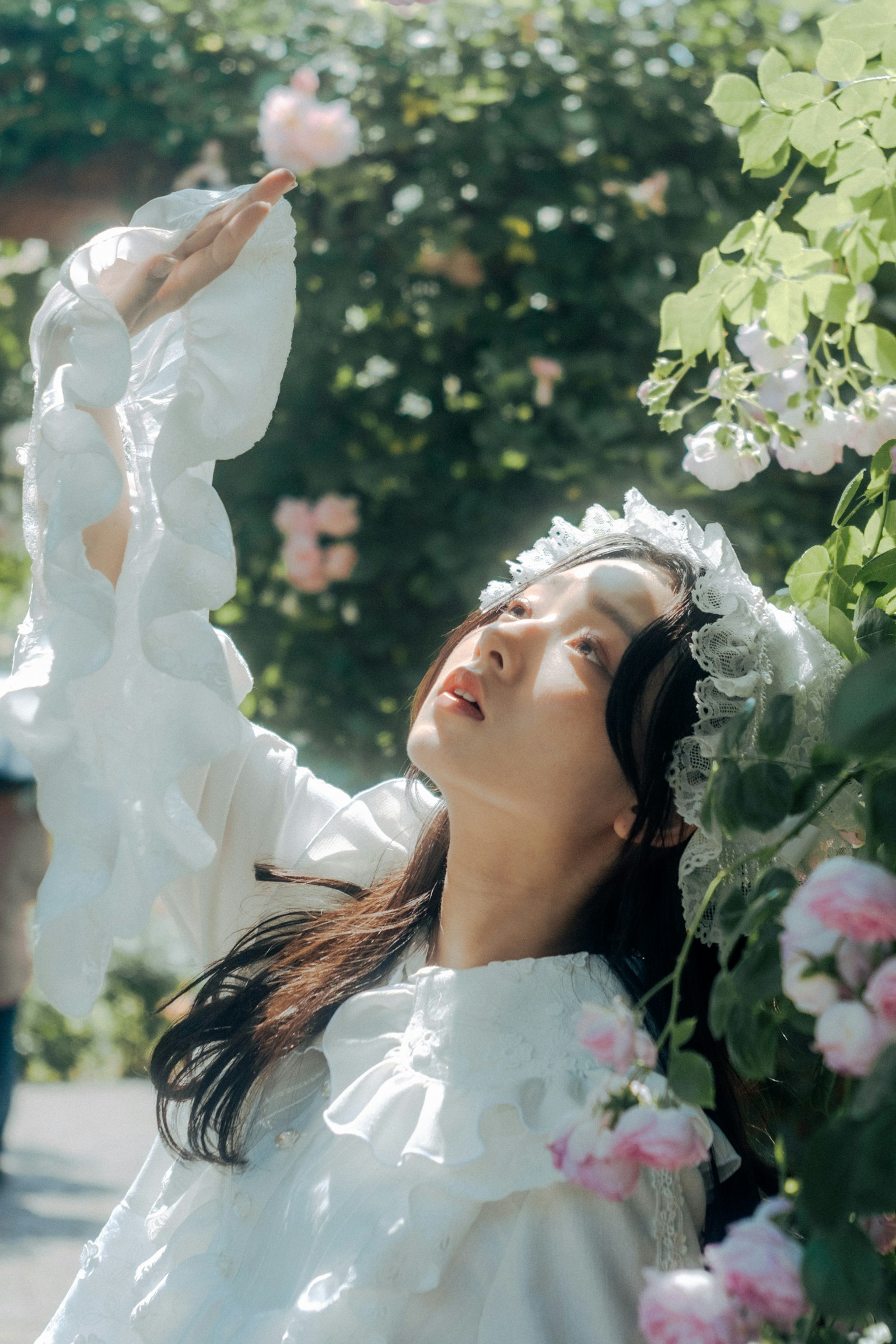 A woman in a white dress raising her hand among flowers