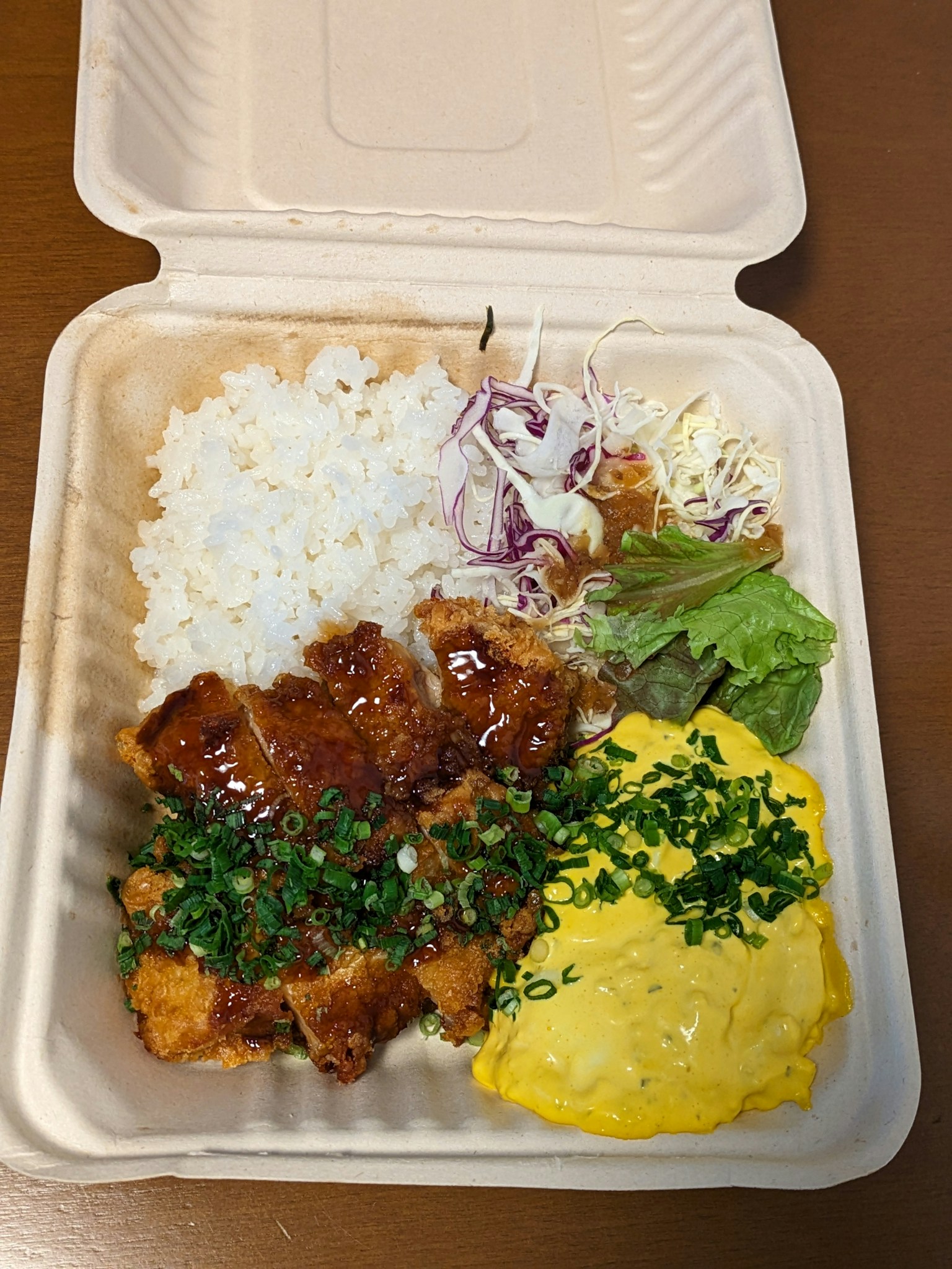 白いご飯、鶏肉の照り焼き、卵、サラダが入った弁当
