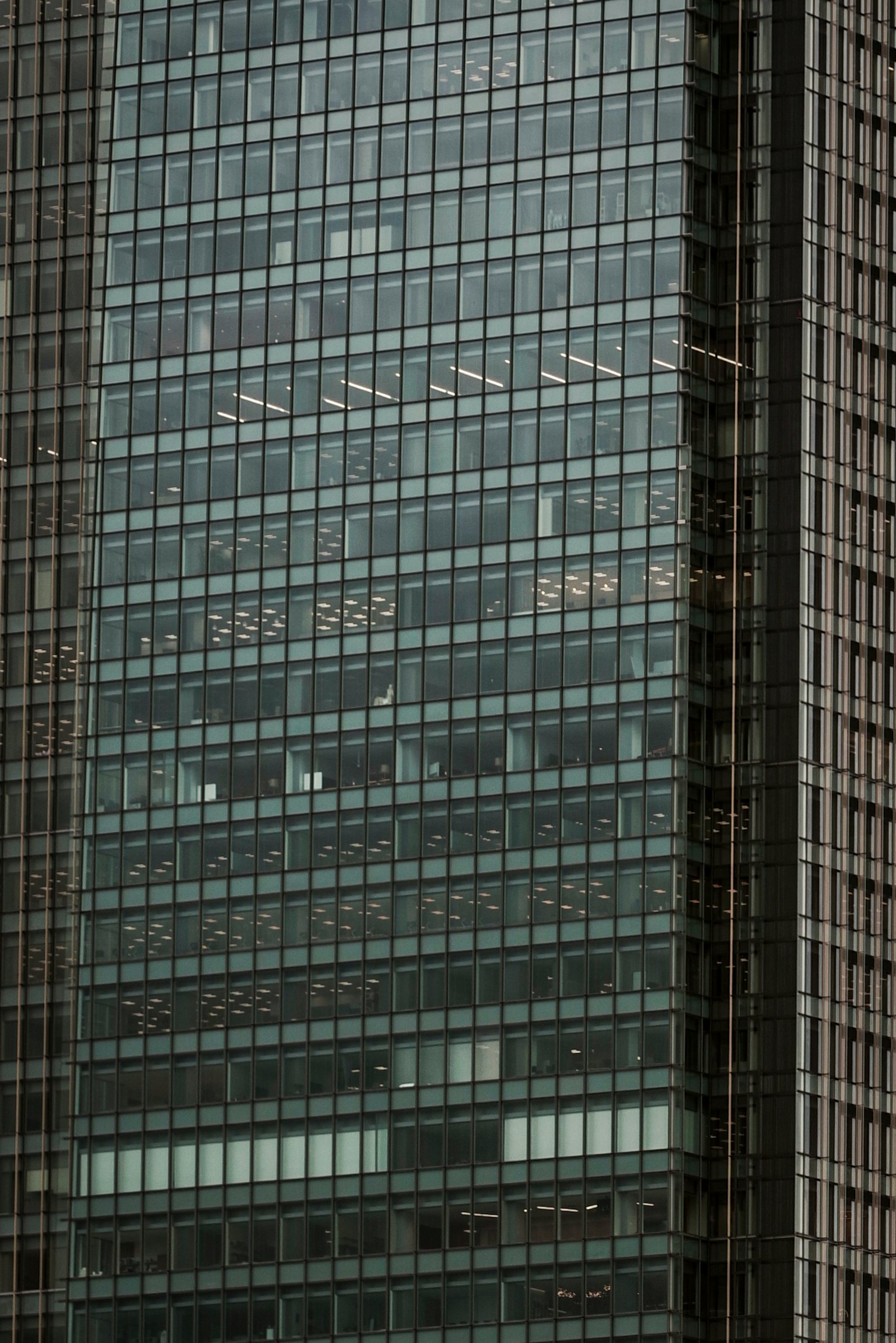 Cận cảnh mặt tiền kính của tòa nhà chọc trời với các phản chiếu và họa tiết ánh sáng và bóng tối