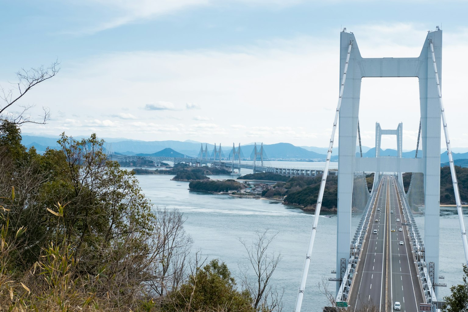 A white bridge stands against a blue sky and river landscape