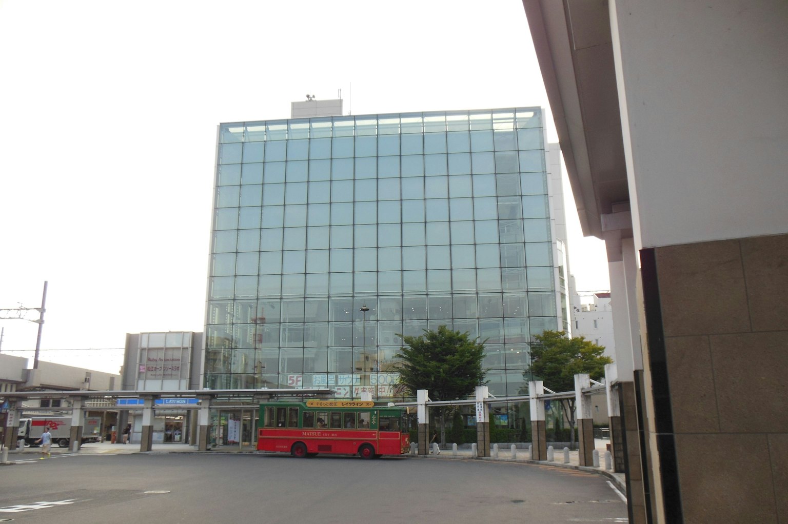 Modernes Glasgebäude mit einem roten Bus im Vordergrund