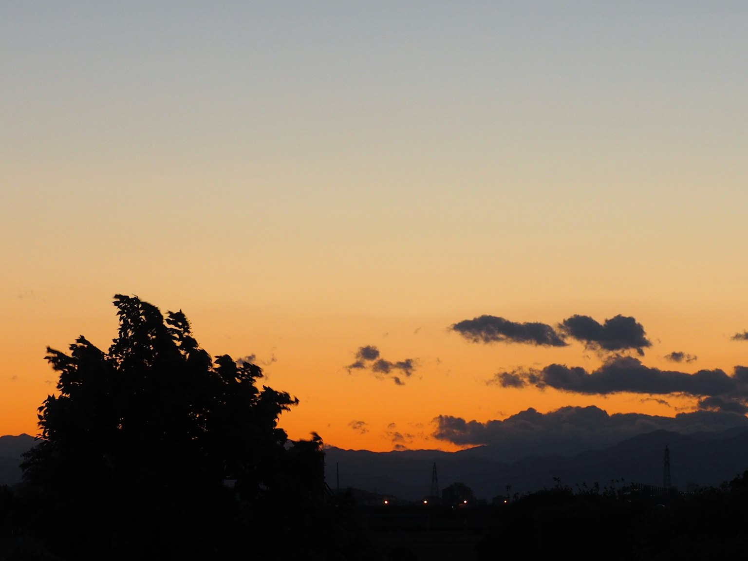 Tramonto panoramico con alberi in silhouette e montagne lontane