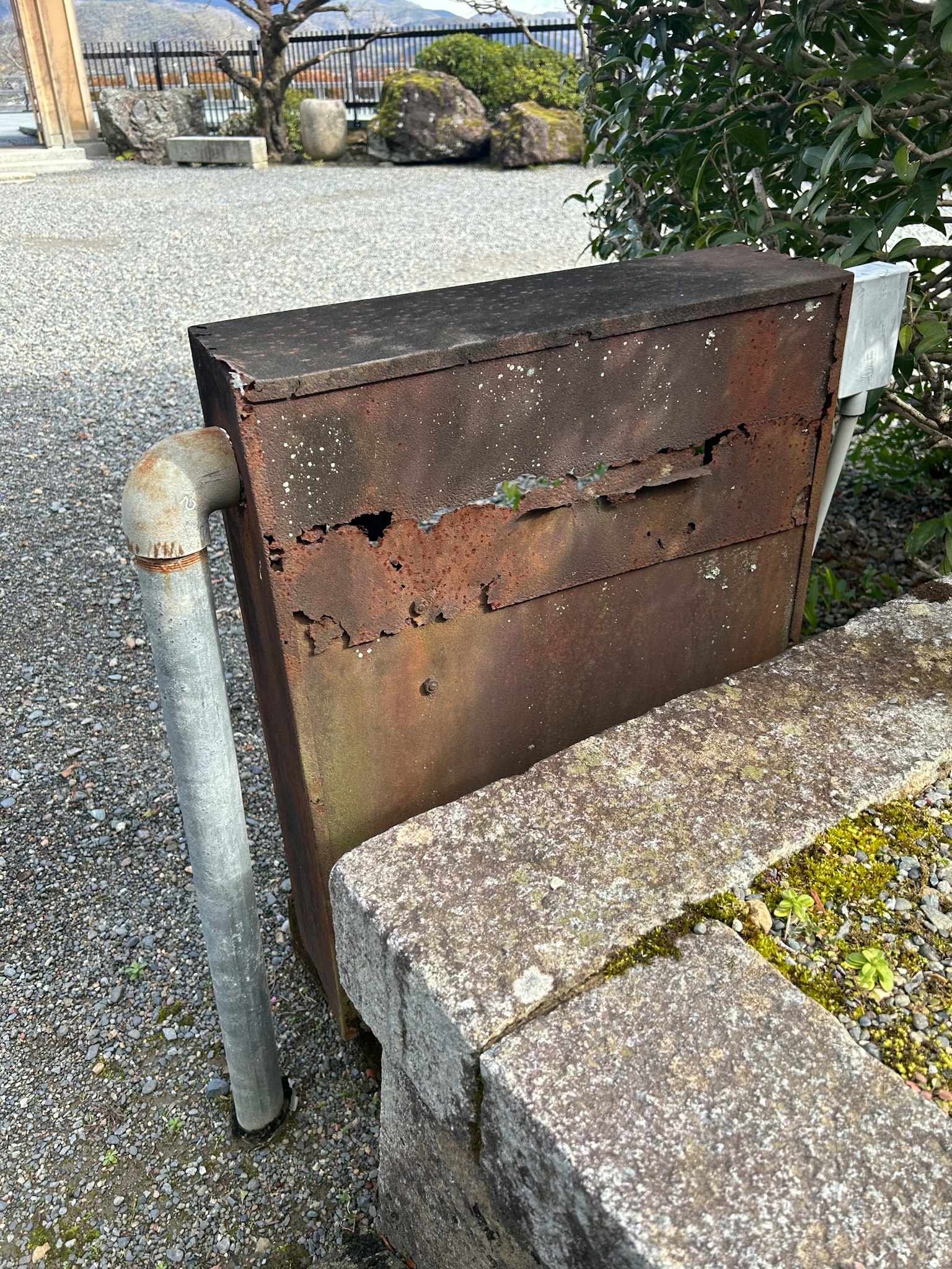 Una scatola di metallo usurata accanto a una piattaforma di pietra