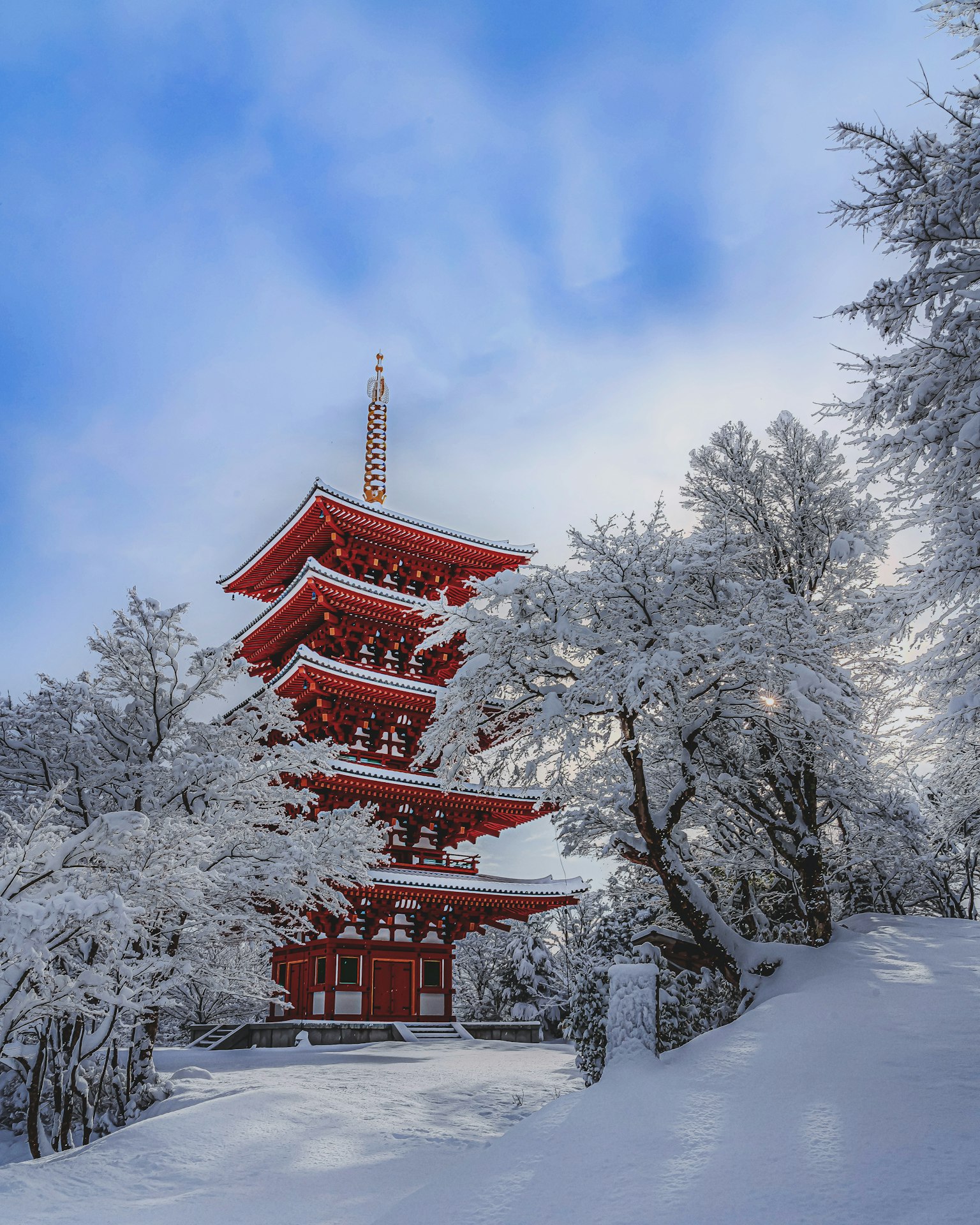 Snow-covered red pagoda surrounded by white trees
