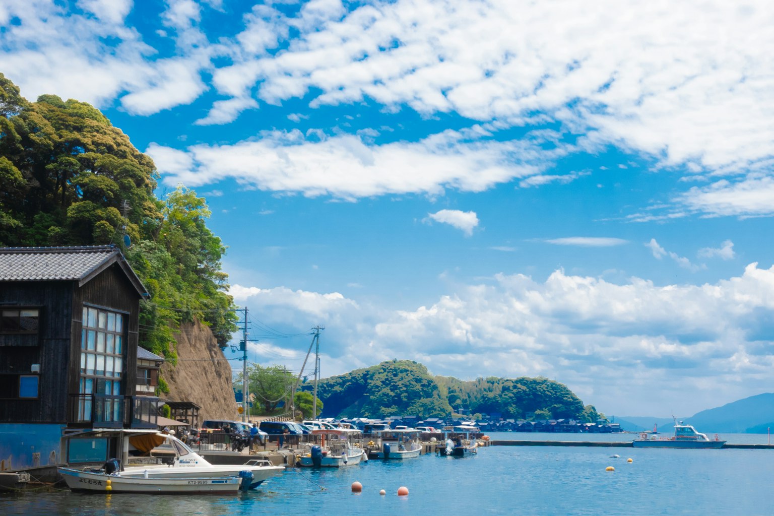 Paysage côtier avec ciel bleu et nuages bateaux amarrés dans un port collines verdoyantes en arrière-plan
