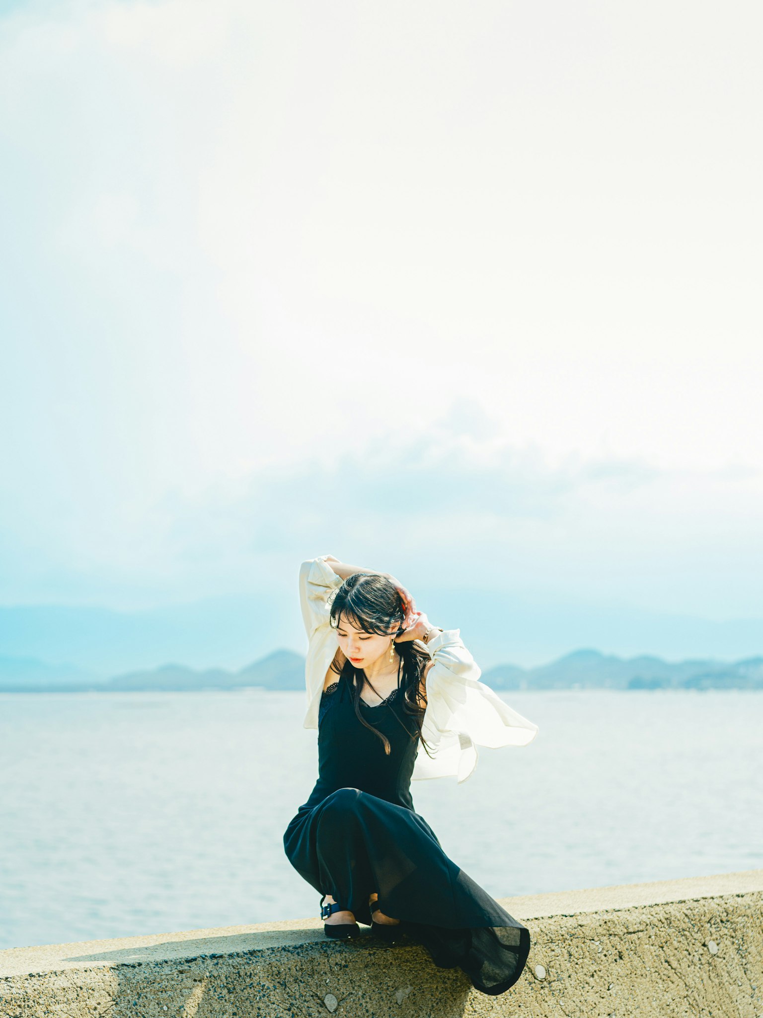 一位女性在海边摆姿势穿着黑色服装和白色围巾