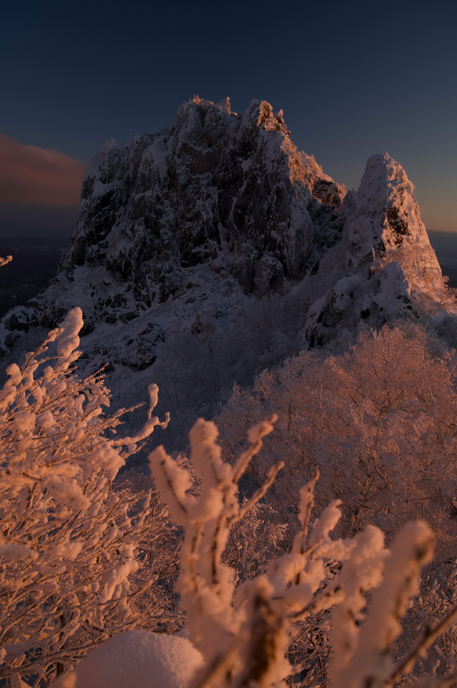 Paysage montagneux rocheux couvert de neige avec une lumière douce du coucher de soleil