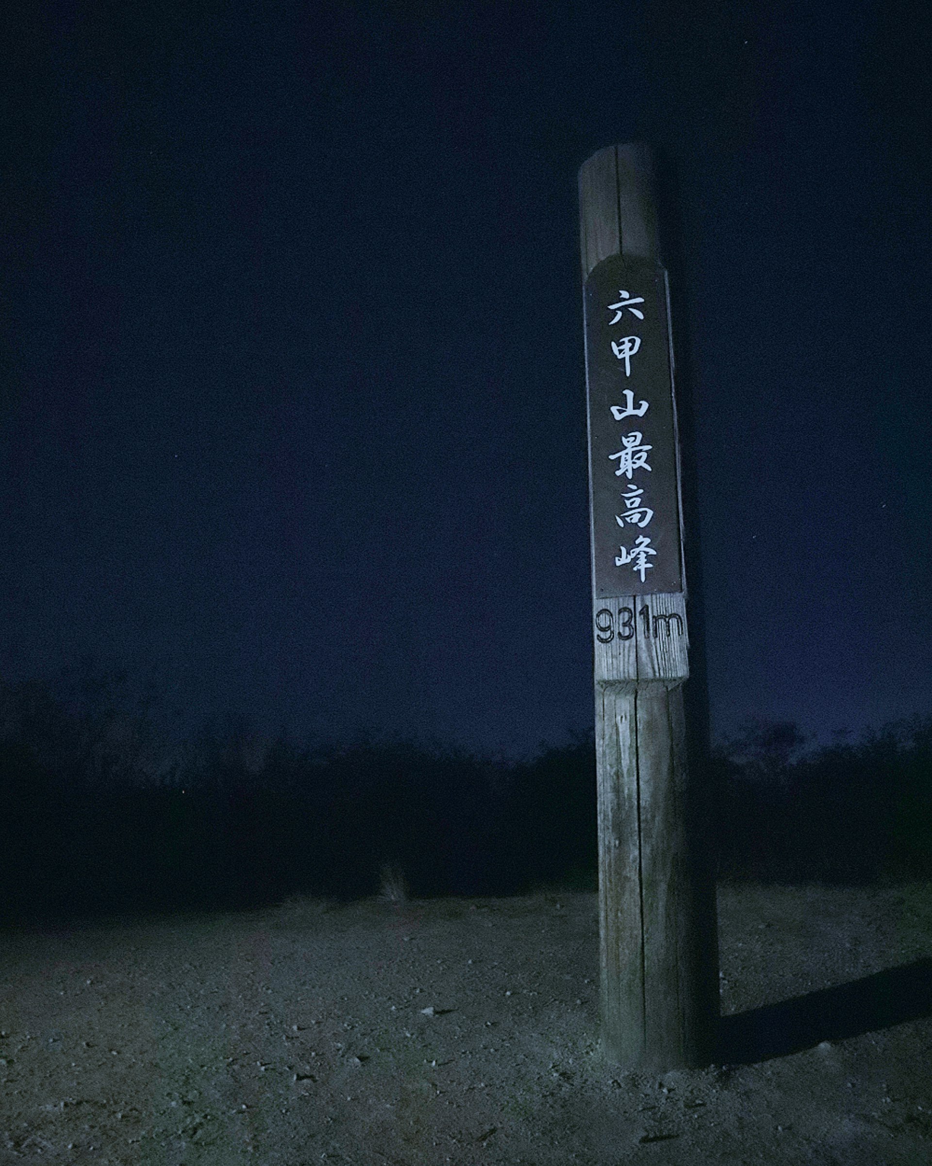 夜の登山道で「六甲山最高峰」と書かれた道標のある風景