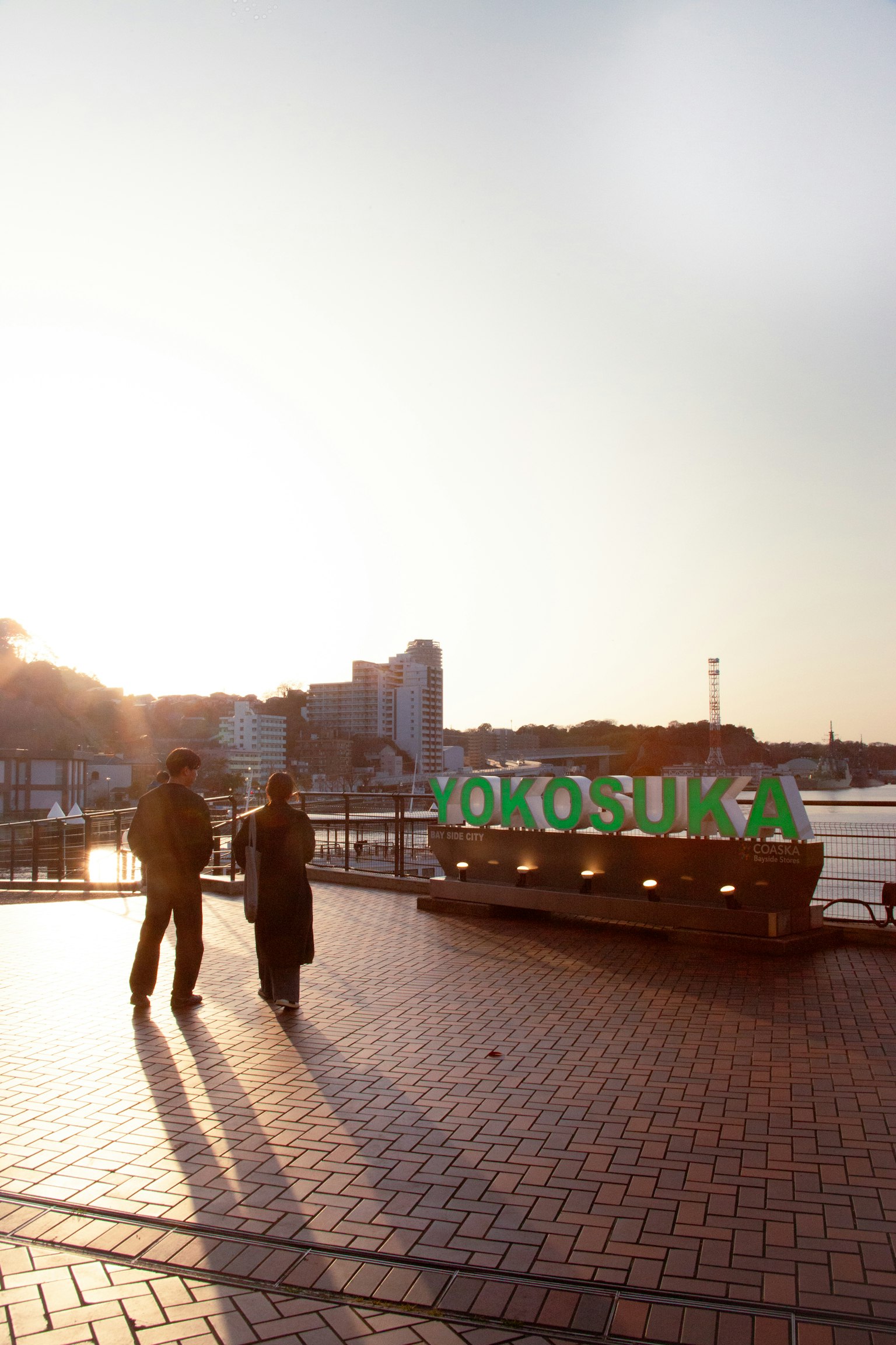 Silhouette của hai người gần biển hiệu Yokosuka vào lúc hoàng hôn