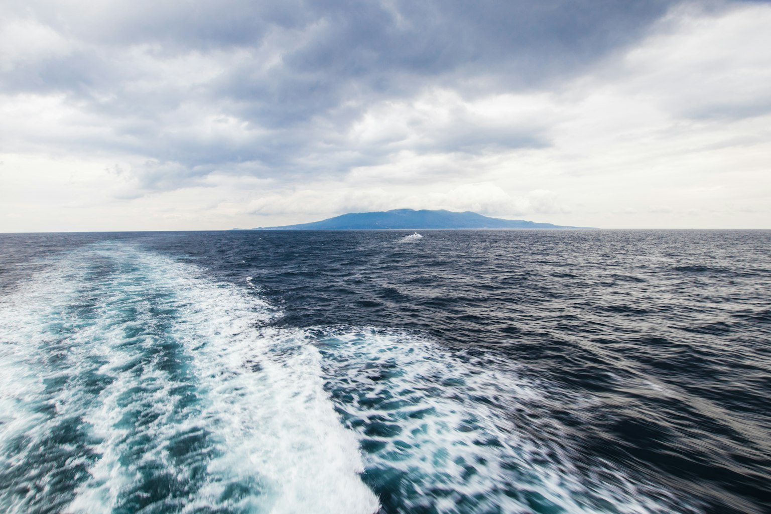 Paisaje con una isla en el horizonte y olas del océano