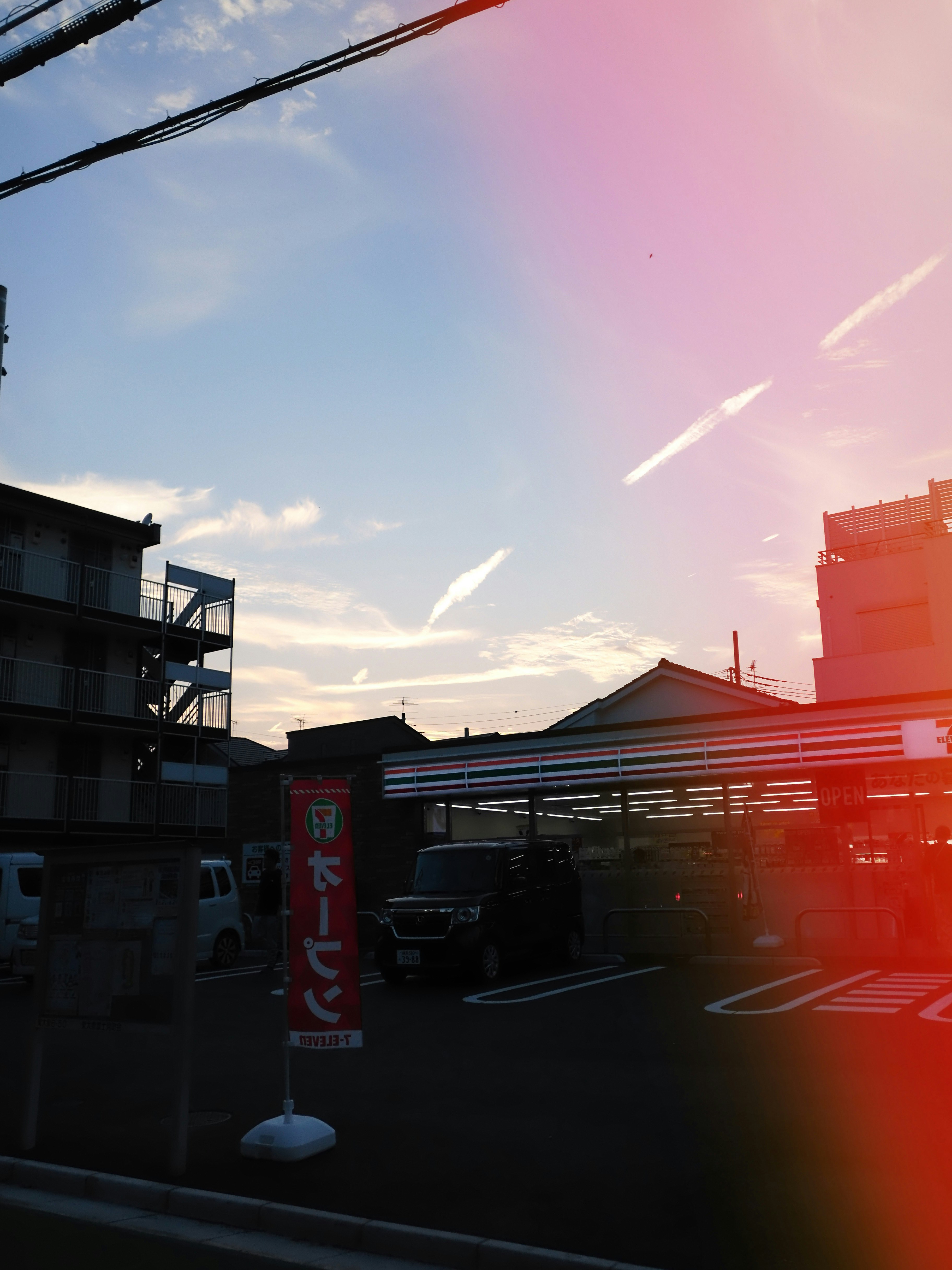 夕暮れの高架下に並ぶ車と街灯のある通り