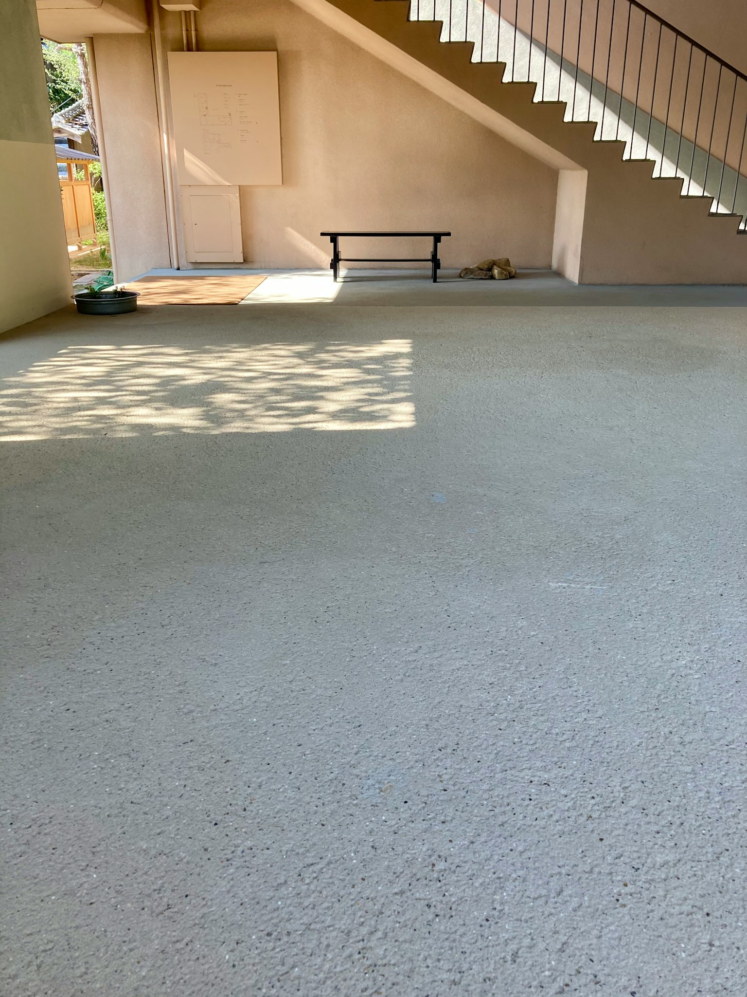 Spacious area under stairs with bright floor and shadow patterns