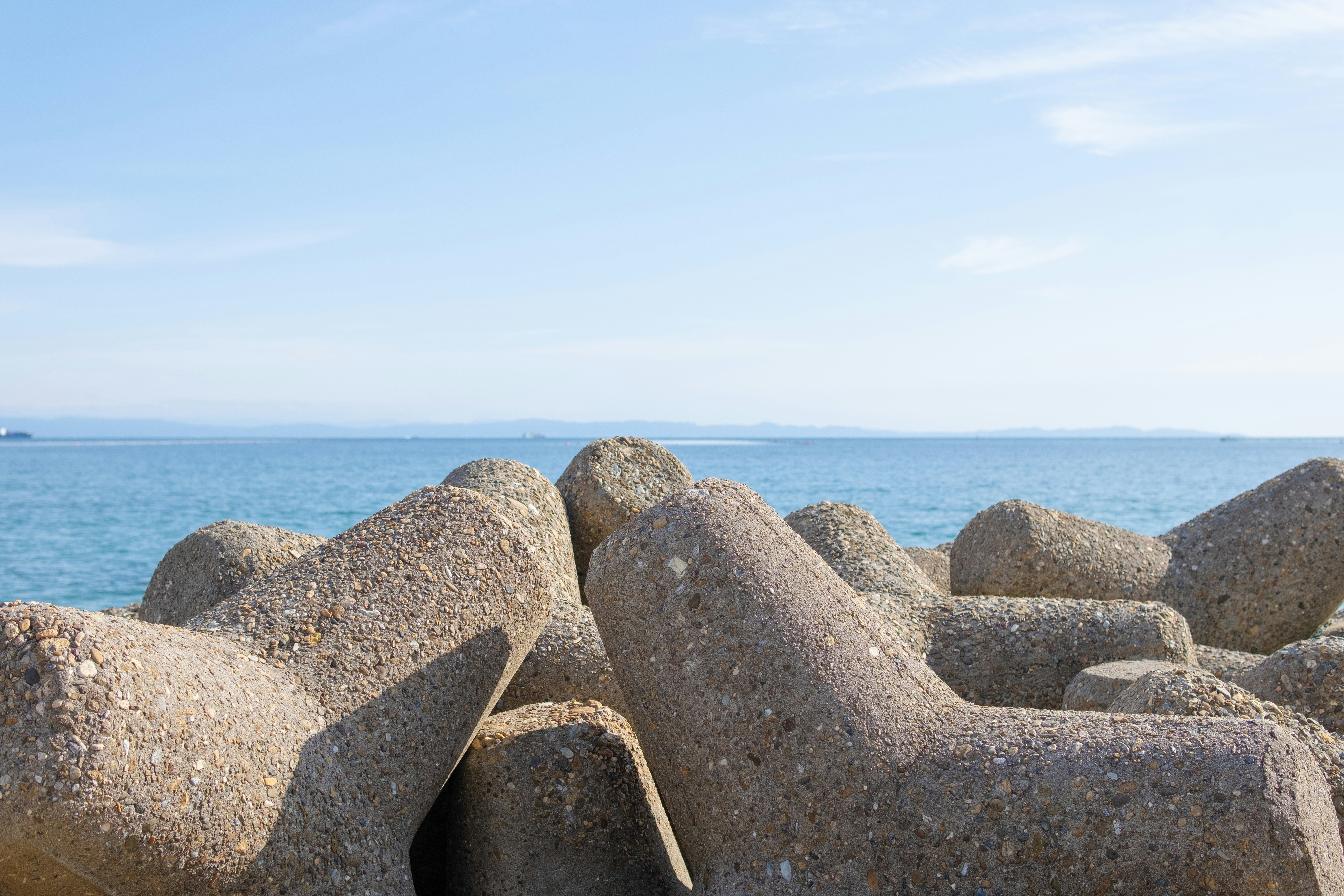 Large breakwater rocks and blue sea shoreline scene