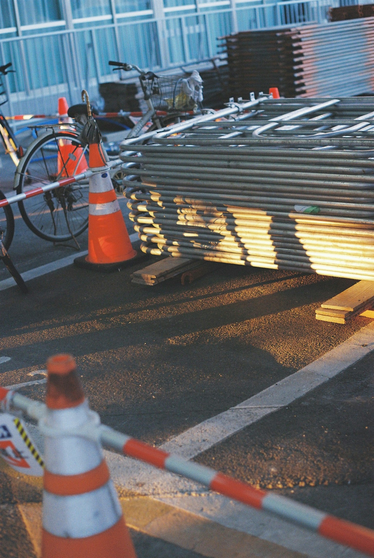 Scena di cantiere con coni di sicurezza e coni arancioni biciclette e materiali metallici visibili