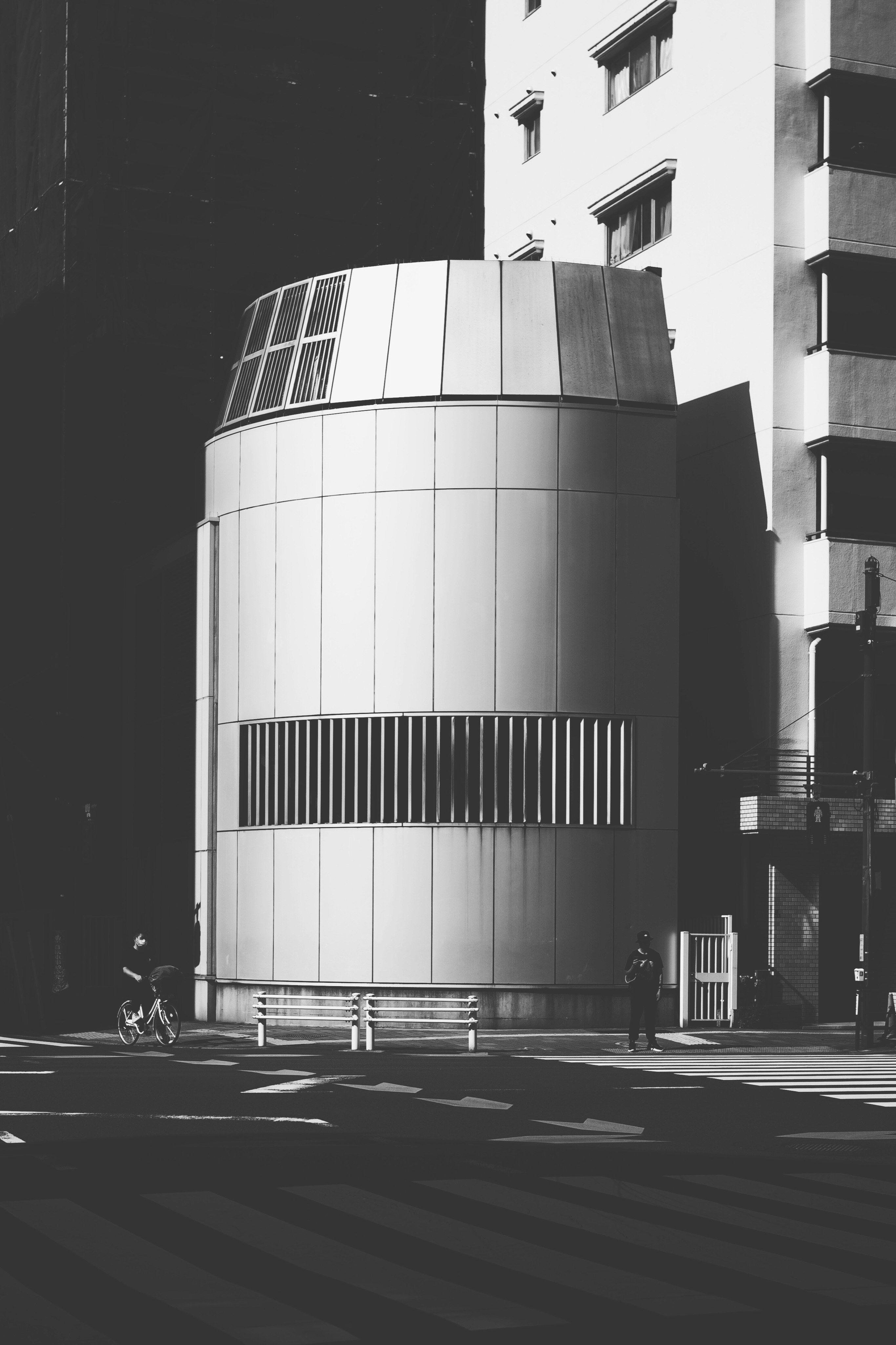 円筒形の建物と高層ビルが並ぶ都市の街角