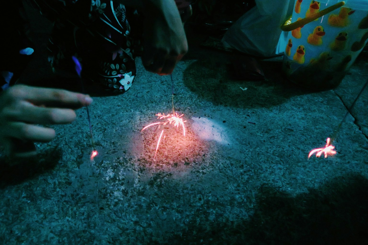 Child's hand lighting sparklers on a dark surface