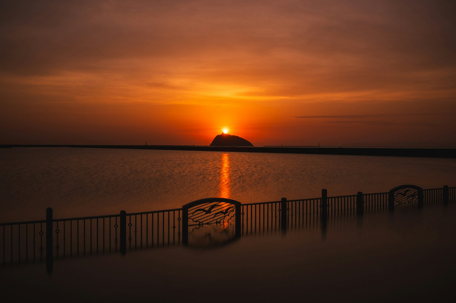 Tramonto che si riflette sull'acqua con una recinzione