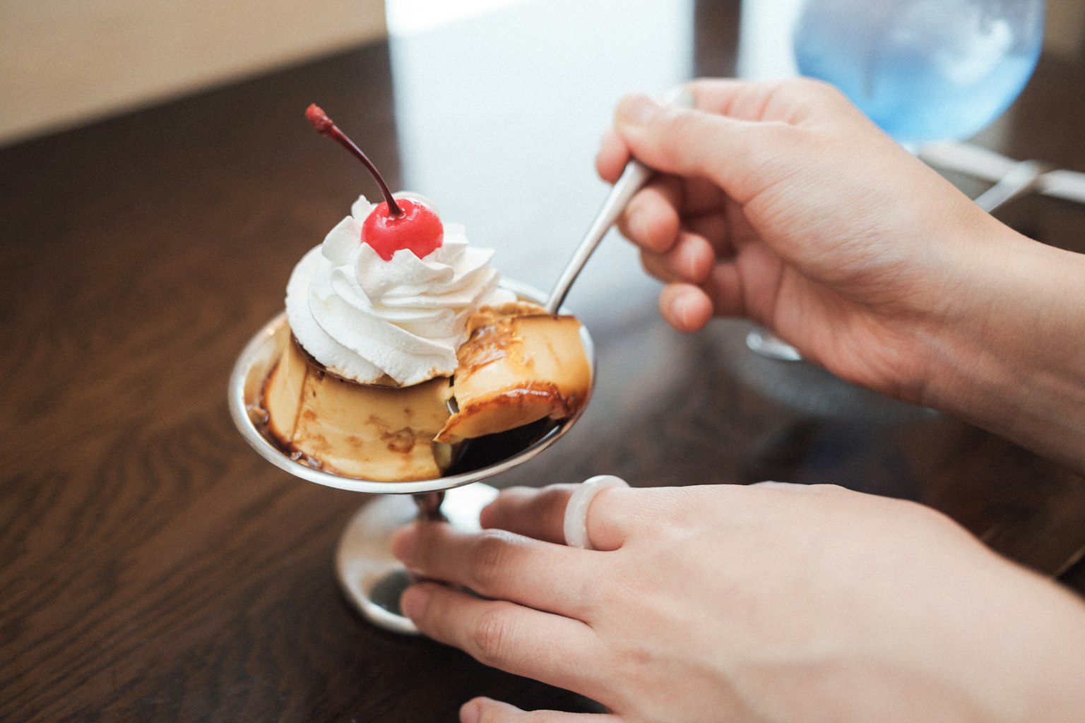 มือที่ถือของหวานที่มีครีมและเชอร์รี่ด้านบน