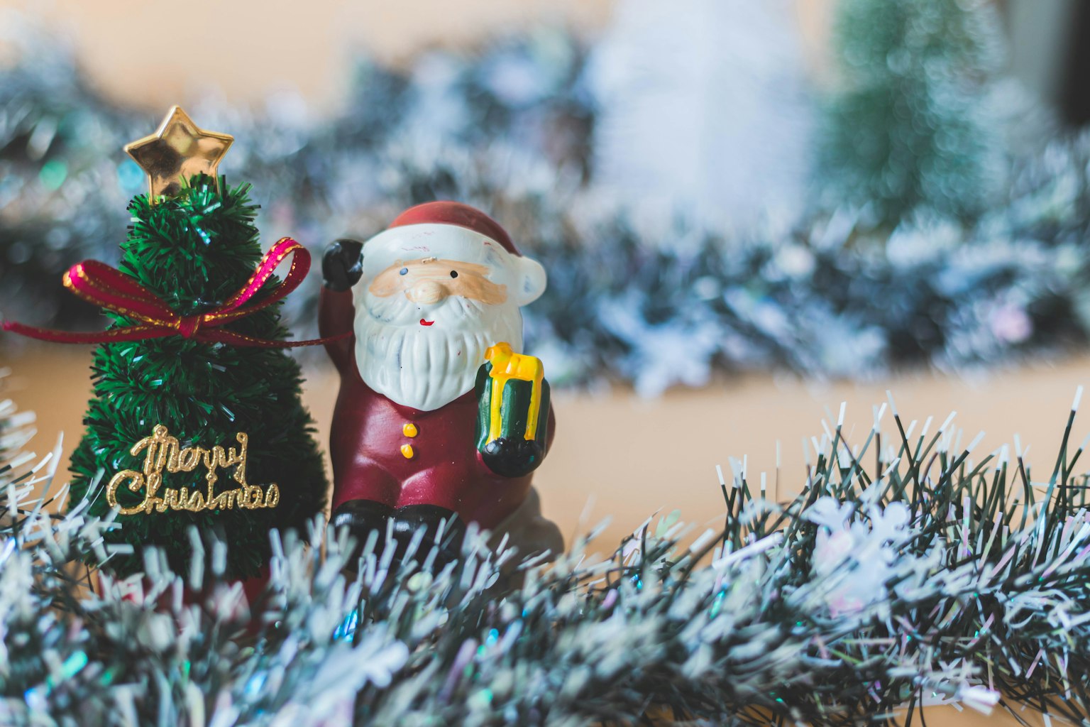 Tượng ông già Noel cầm quà bên cạnh cây thông Noel nhỏ