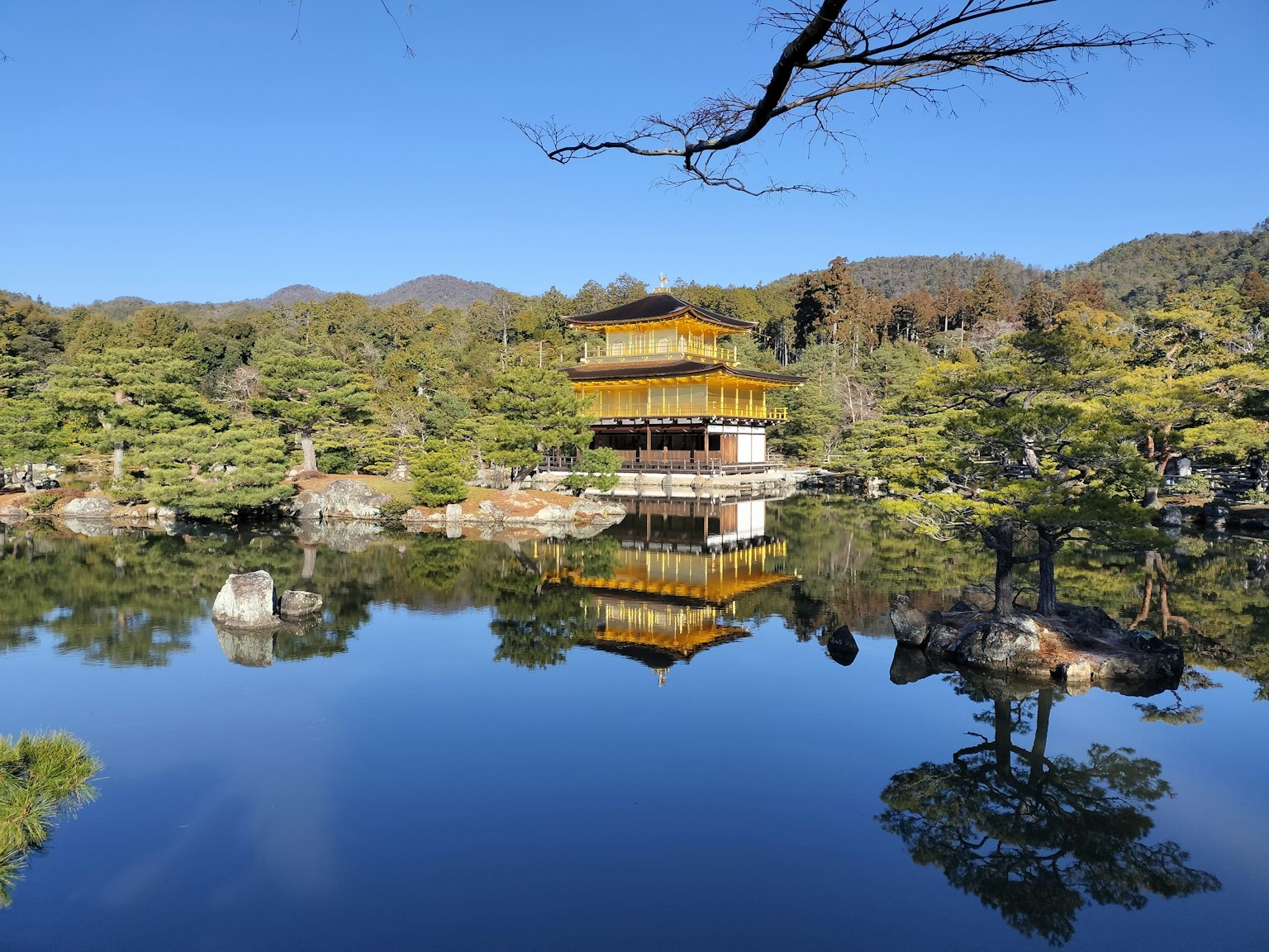 Il Kinkaku-ji che si riflette nello stagno tranquillo in un paesaggio sereno