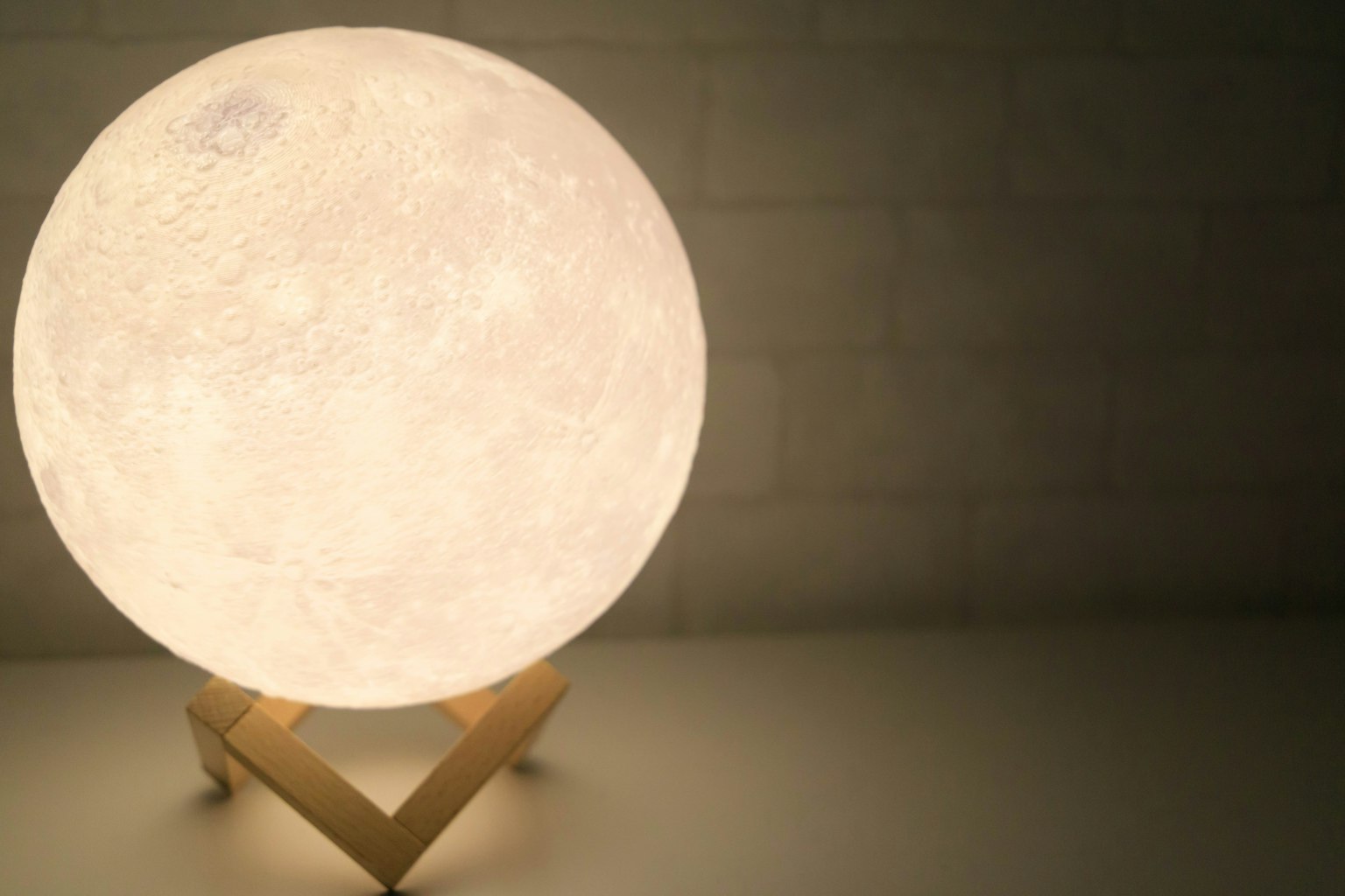 Lampu berbentuk bulan yang cerah di atas dudukan kayu