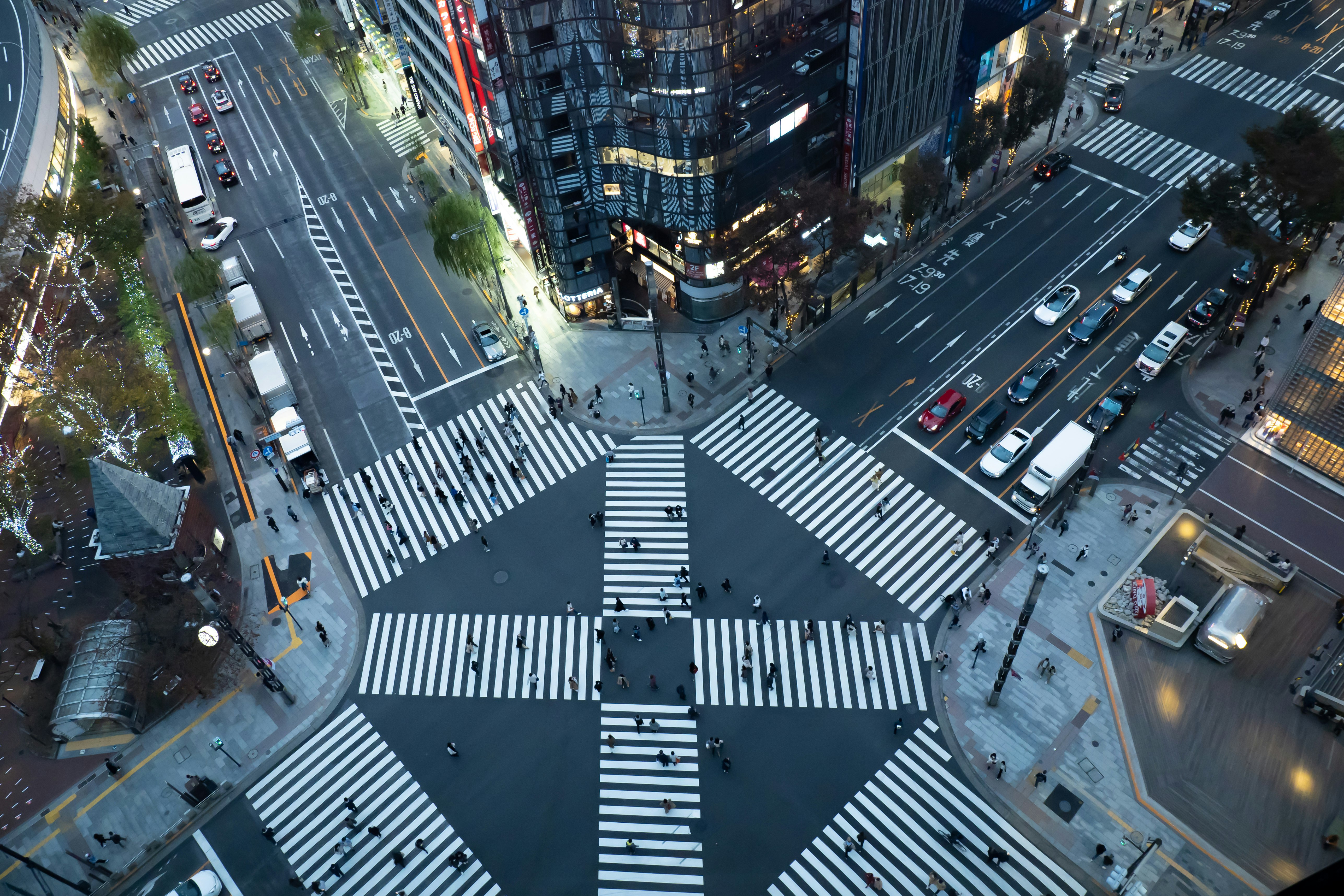 高層ビルと交差点の上空からの視点で車と人が行き交う繁忙な都市風景