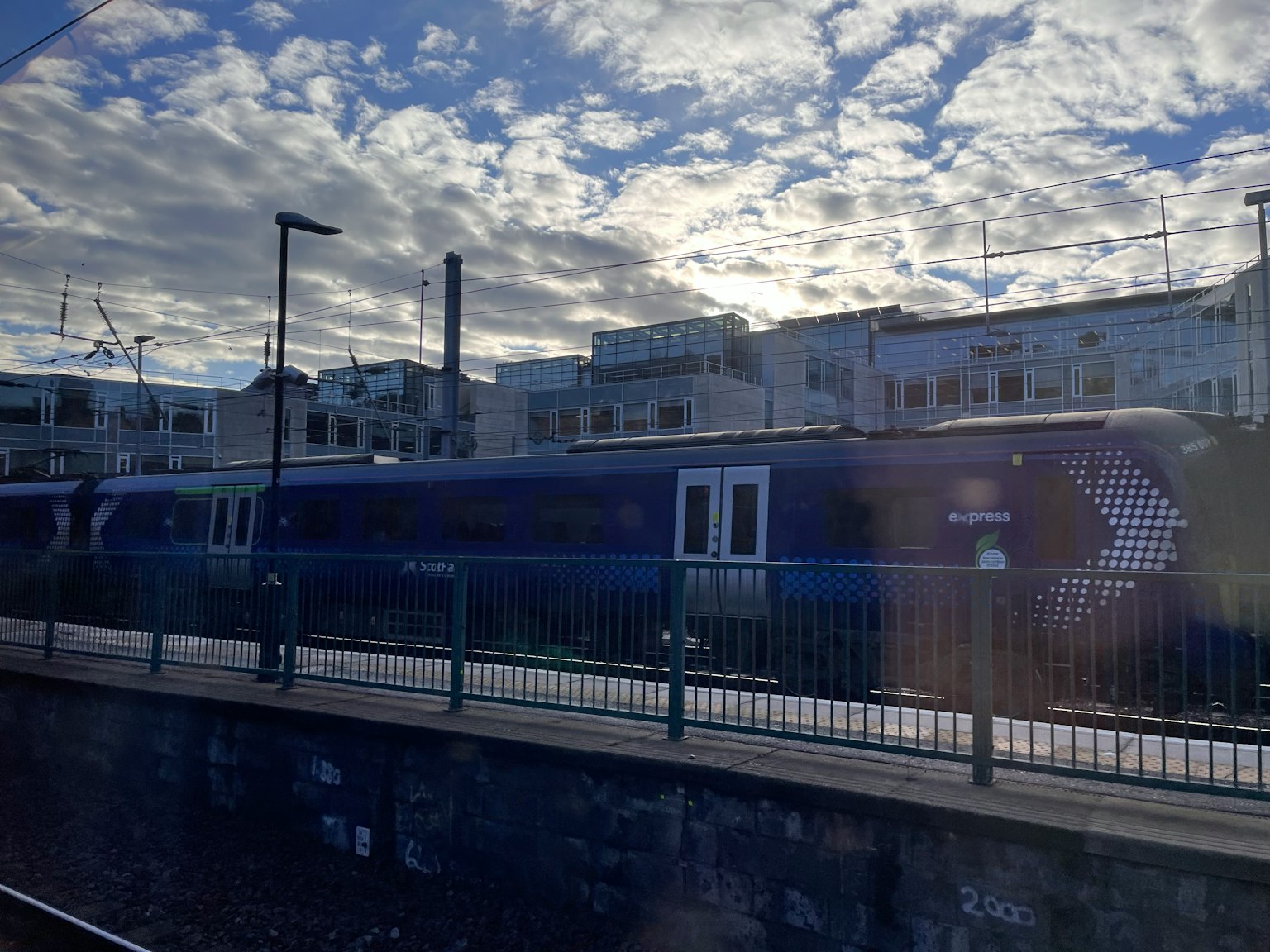 藍色火車停在車站，背景是多雲的天空