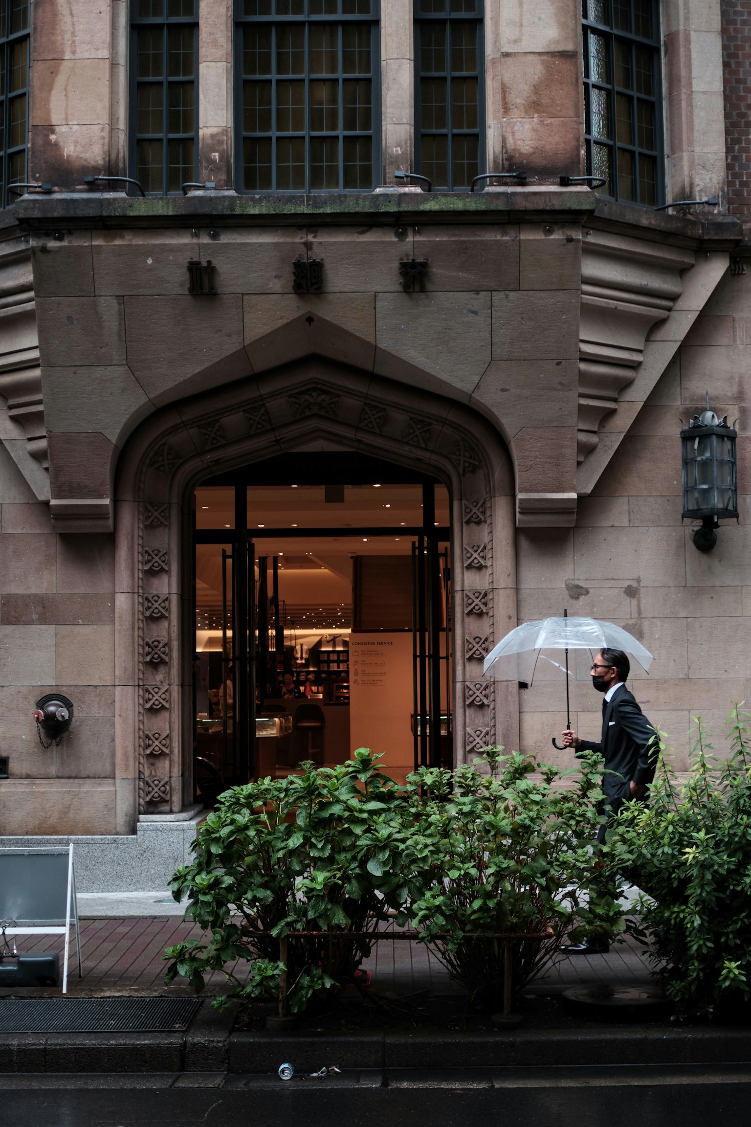 Un homme tenant un parapluie marche devant un vieux bâtiment sous la pluie