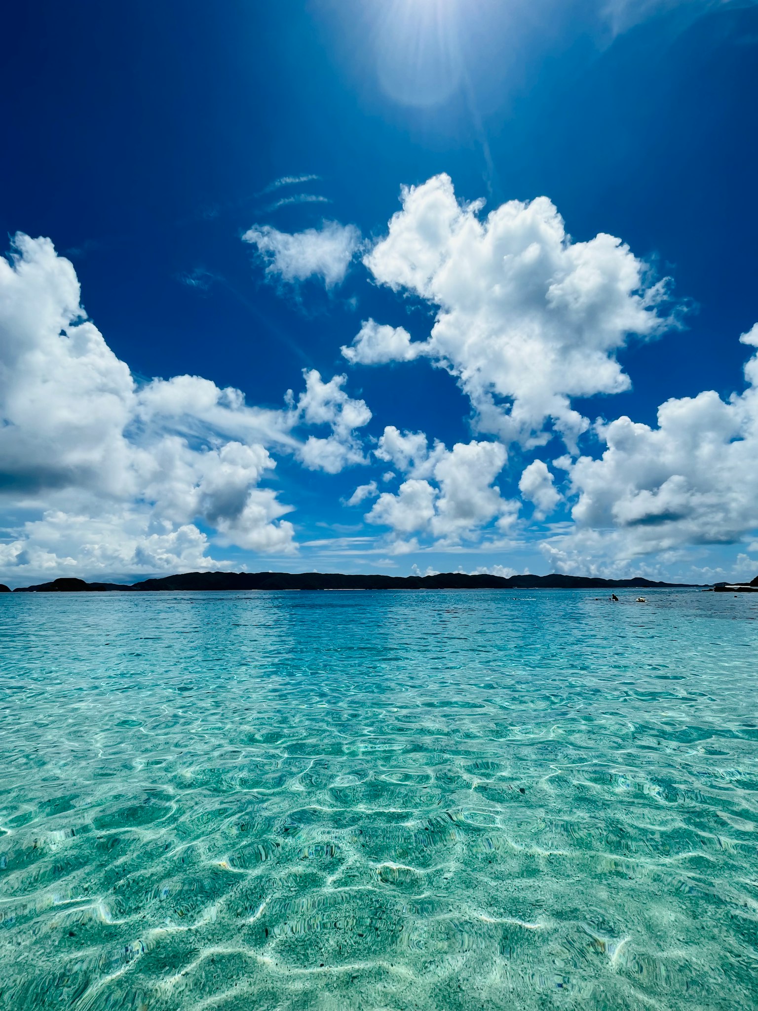 Une vue sereine de l'océan avec une eau turquoise claire et des nuages blancs duveteux