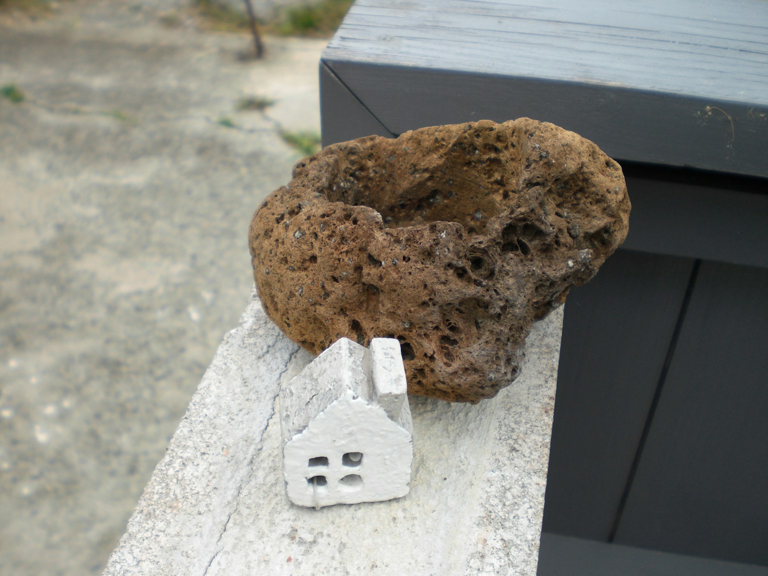 Un piccolo modello di casa bianca accanto a un grande oggetto simile a una roccia