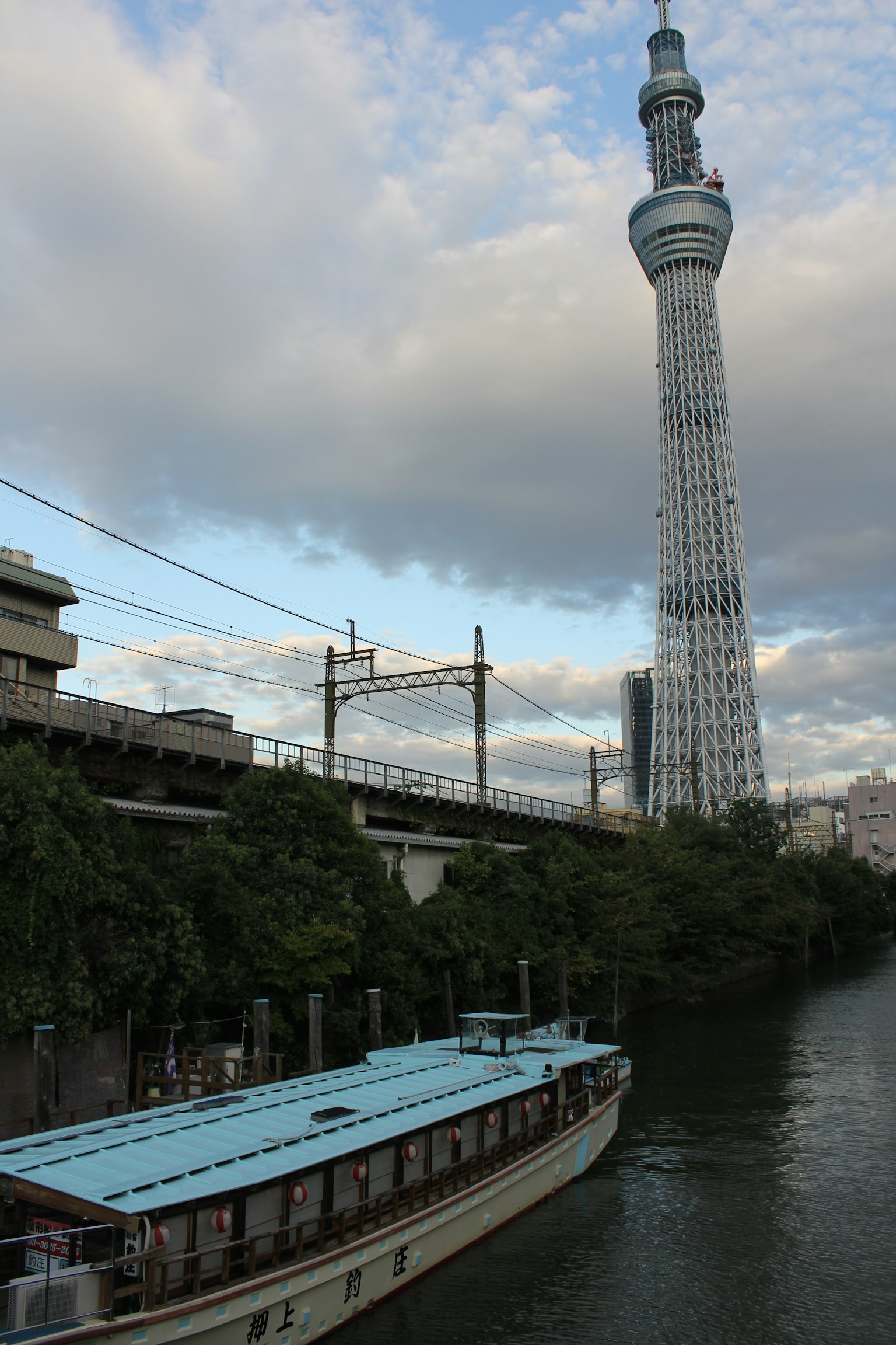Tokyo Skytree bên cạnh sông Sumida với một chiếc thuyền đi qua