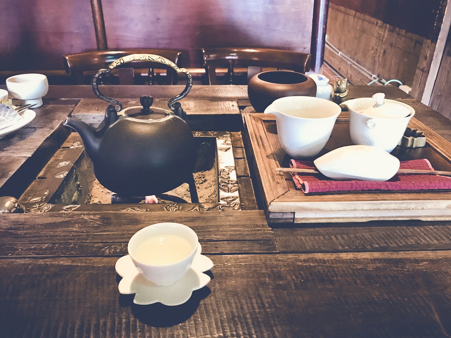 木桌上的茶具，包括黑色茶壶和白色茶杯