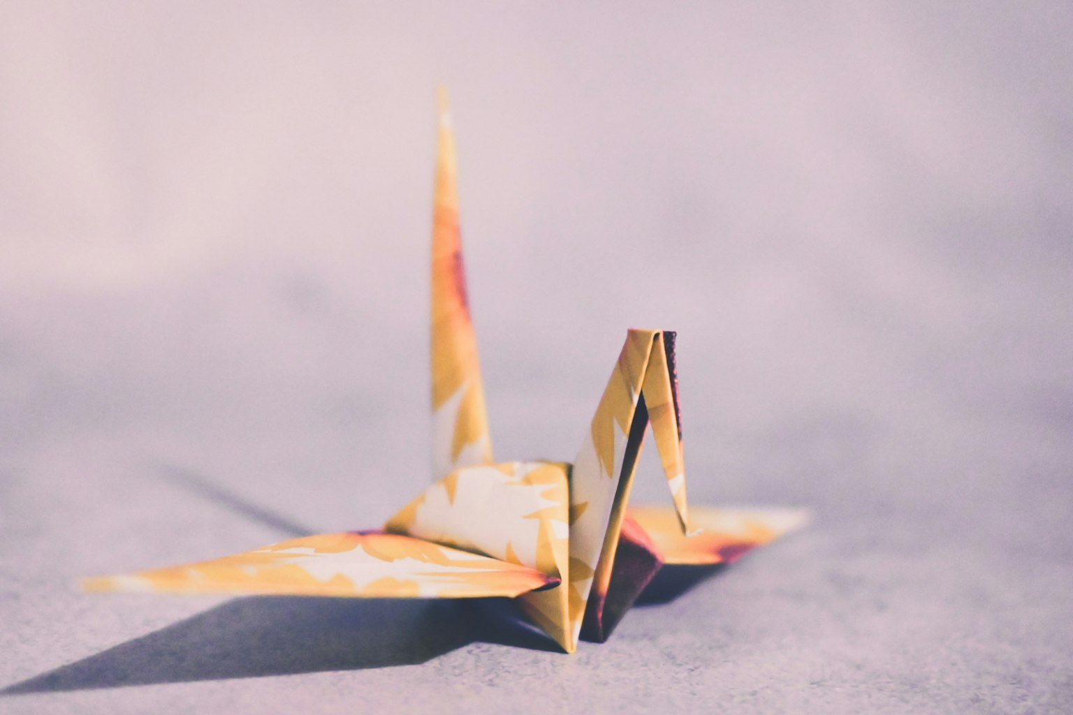 Sebuah burung bangau origami berwarna cerah diletakkan di atas permukaan lembut