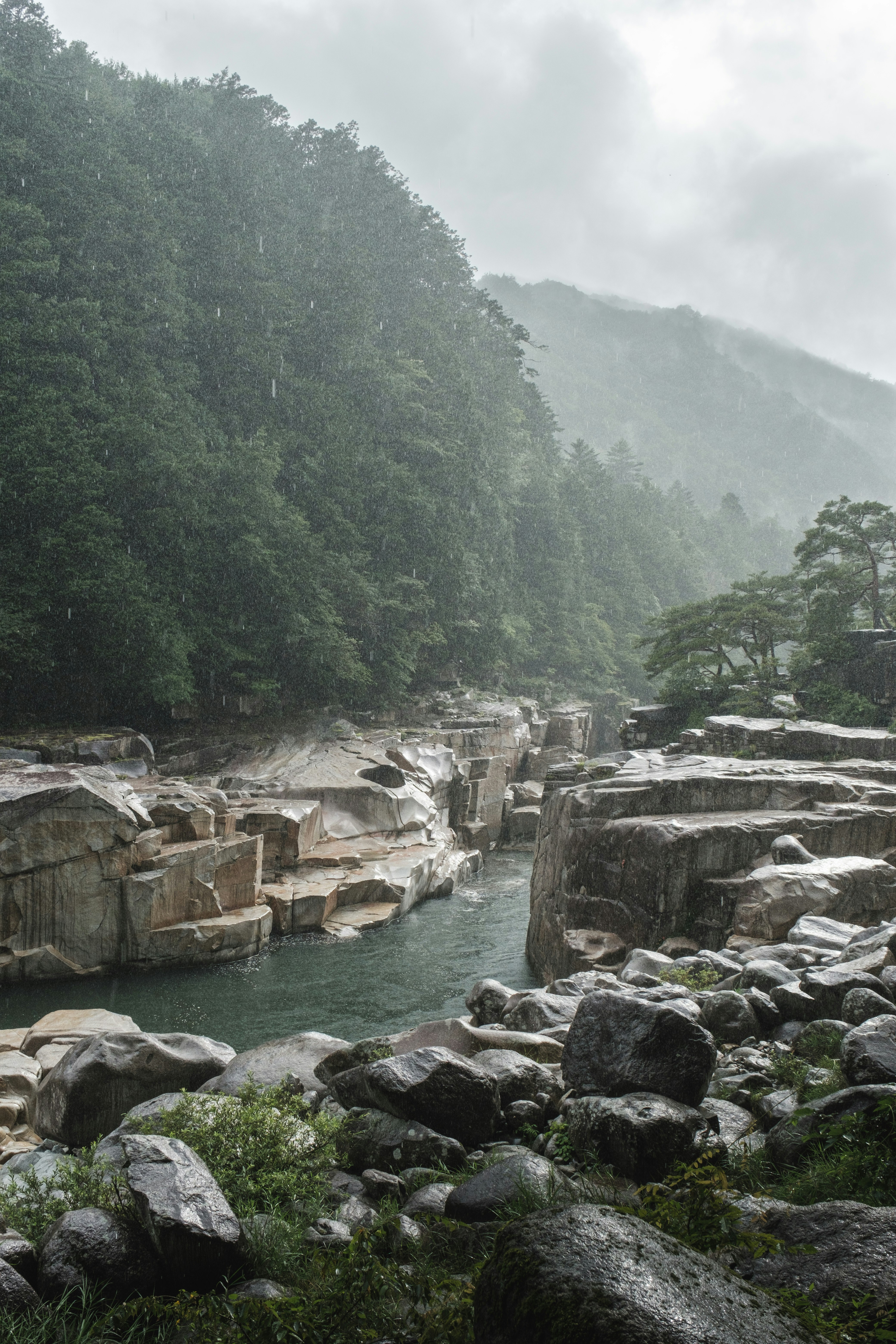Fiume nebbioso con sponde rocciose e acqua a cascata
