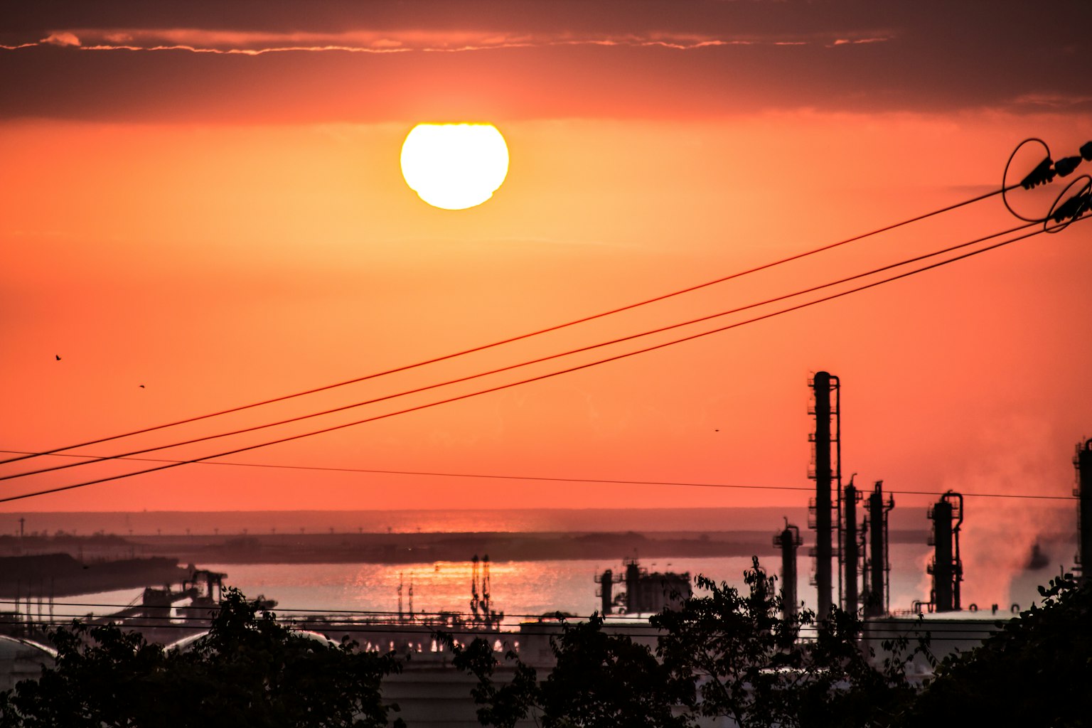 Industrial landscape at sunset with orange sky and silhouette of structures